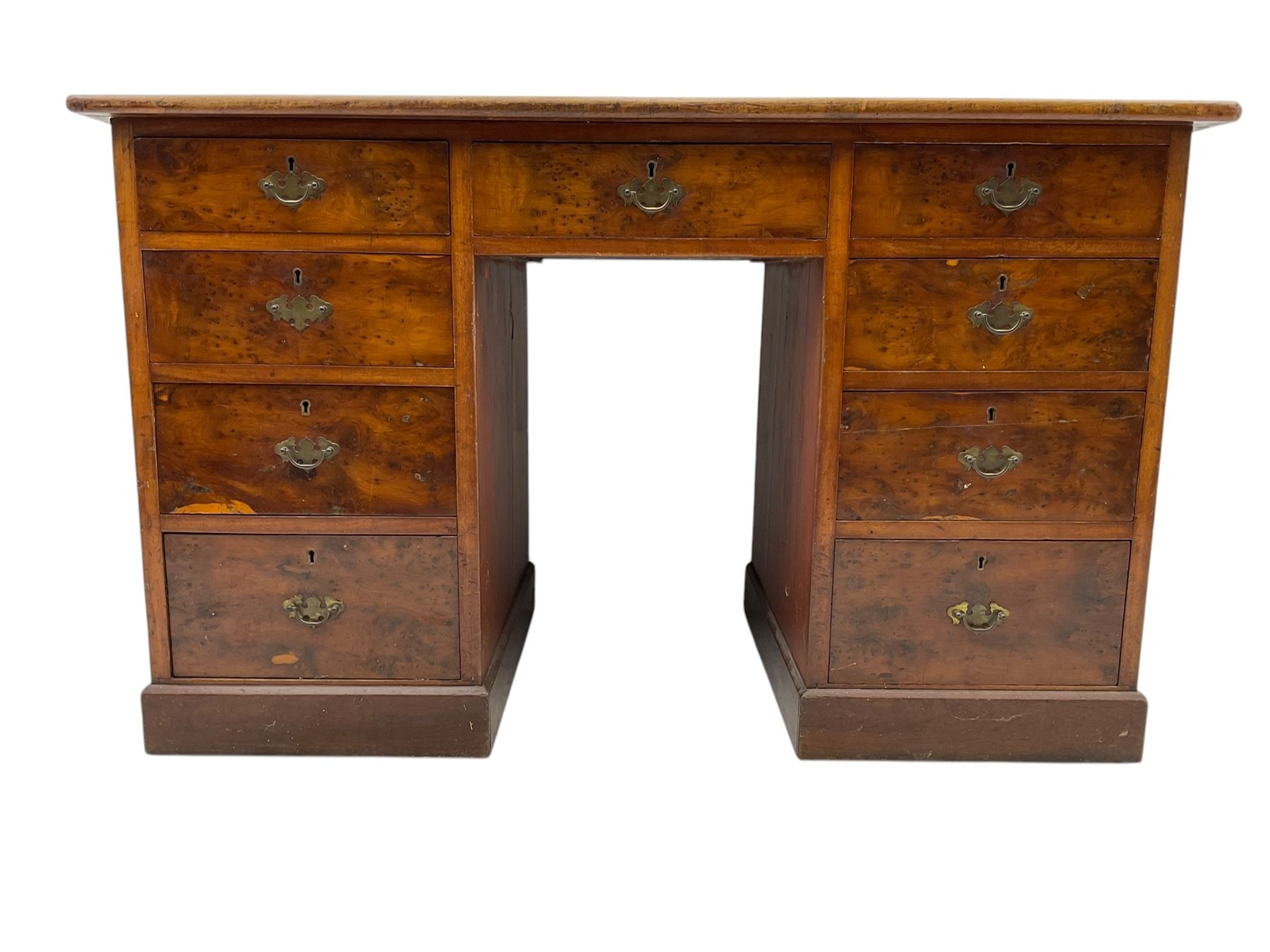 Late 19th to early 20th century walnut pedestal desk, rectangular top inset with red tooled leather writing surface, over a central frieze drawer flanked by two pedestals, each fitted with four graduated drawers with brass escutcheons and drop handles, the whole raised on a plinth base