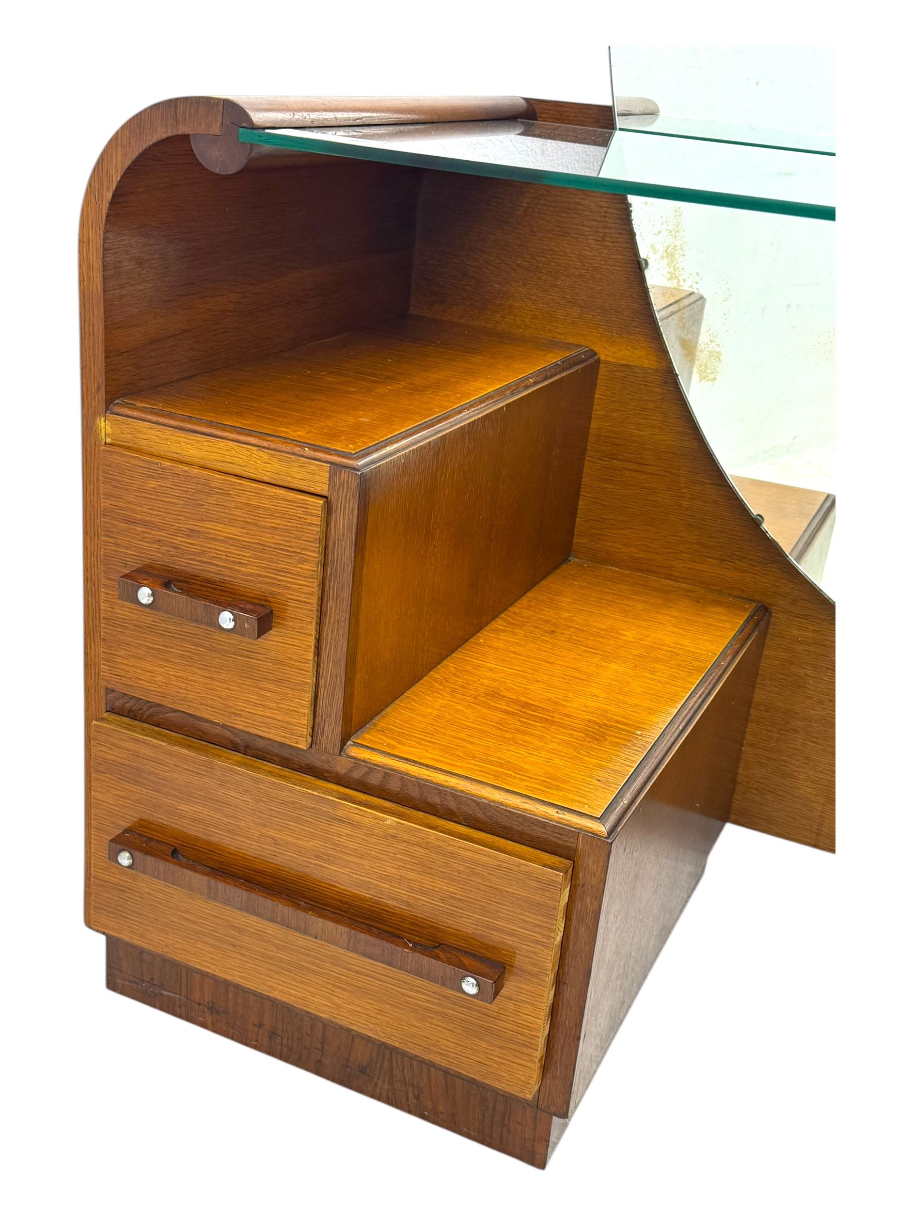 Early 20th century Art Deco walnut dressing table, featuring a large oval triptych mirror above a stepped base, fitted with four drawers and a central glass shelf, all raised on a plinth base