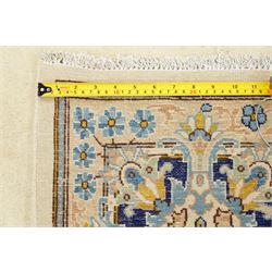 South East Persian Kirman hand-knotted carpet, ivory field with central floral medallion in tones of cobalt and pale blue, issuing scrolling vinery and palmettes, conforming spandrels, main border with scrolling foliage and stylized palmettes, framed by multiple guard borders, with cotton fringe ends 