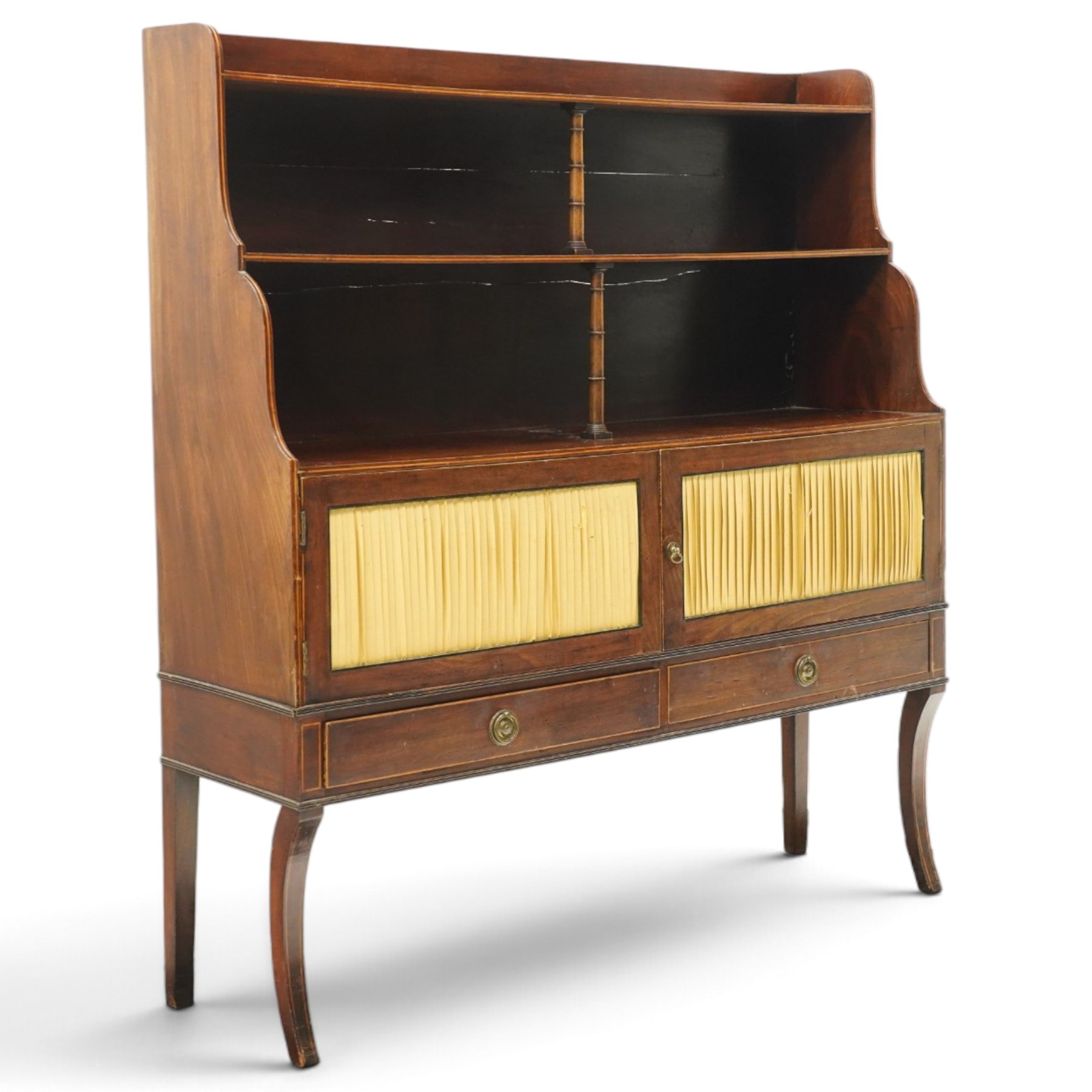 Regency period mahogany waterfall-bookcase chiffonier, the raised back with two open shelves supported by central ring-turned pilasters, fitted with twin doors with sage-green pleated fabric facias, over two drawers with satinwood stringing, raised on front sabre supports