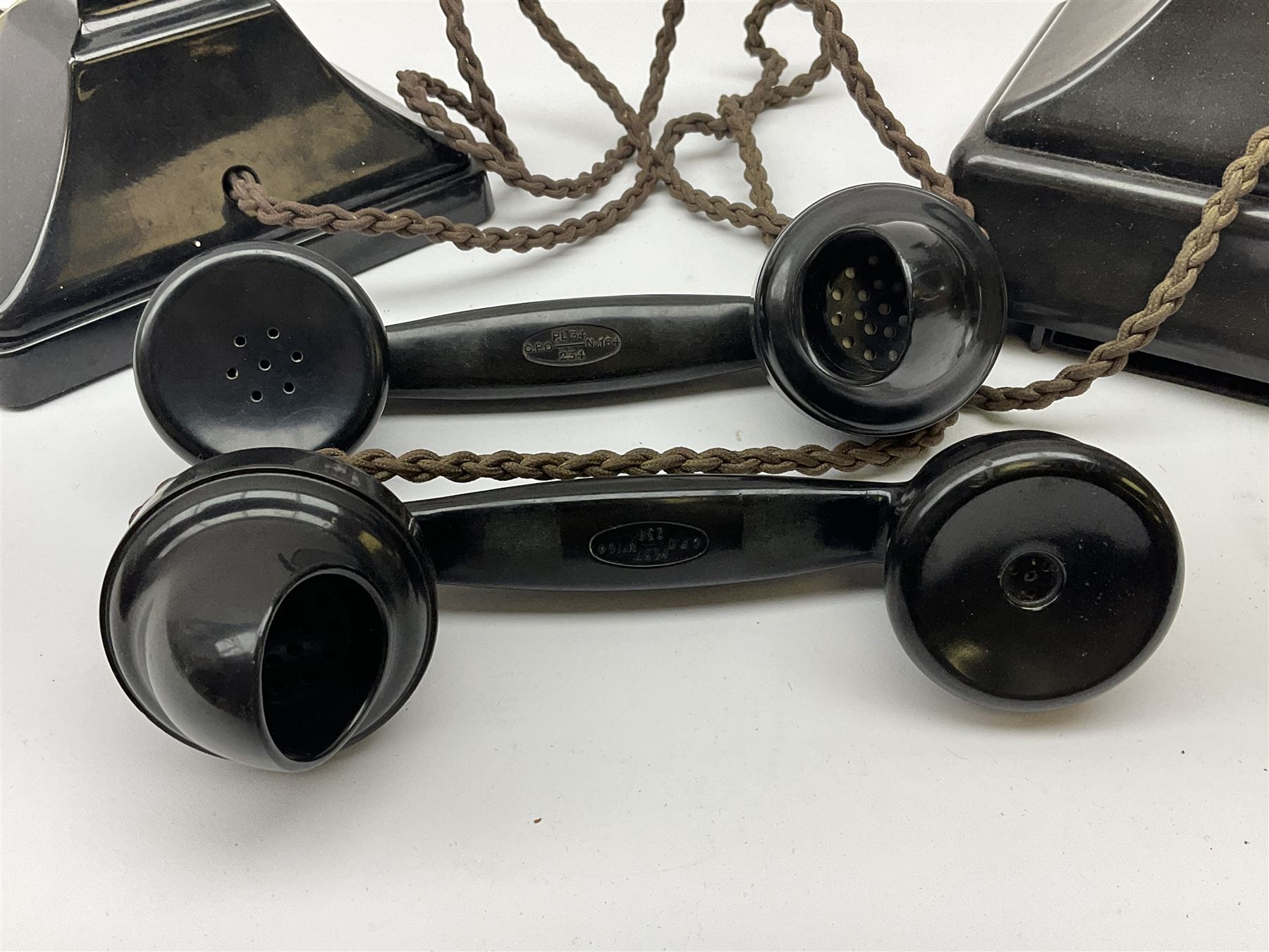 Two black Bakelite telephones of pyramid form with rotary dials, comprising The Telephone Demonstration Set model. 6al with base drawer and light bulb, and another larger with G.P.O FWR 58/2 stamped marks beneath, largest H18cm W20cm D16cm