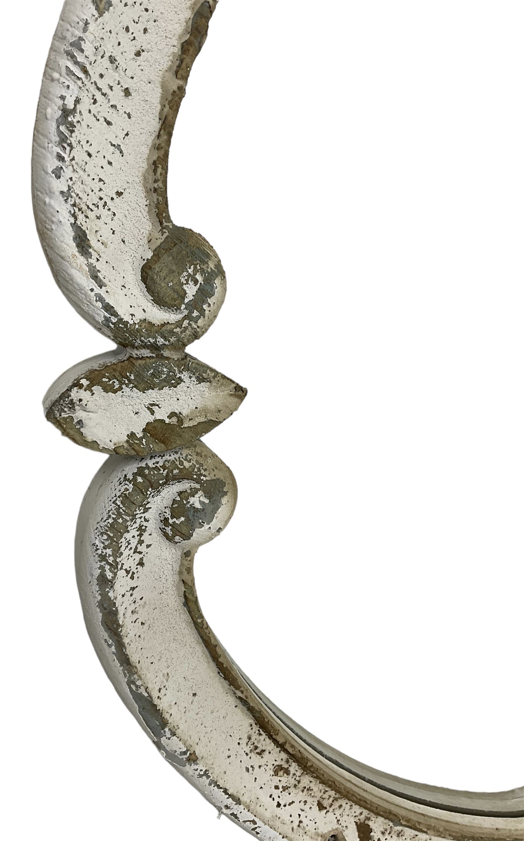 French design carved pine wall mirror, the frame in the form of conforming c-scrolls, plain mirror plate, in distressed white paint finish 