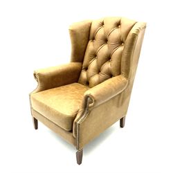 Georgian style wing back armchair upholstered in buttoned and studded tan leather, scrolling arms, square tapering supports 