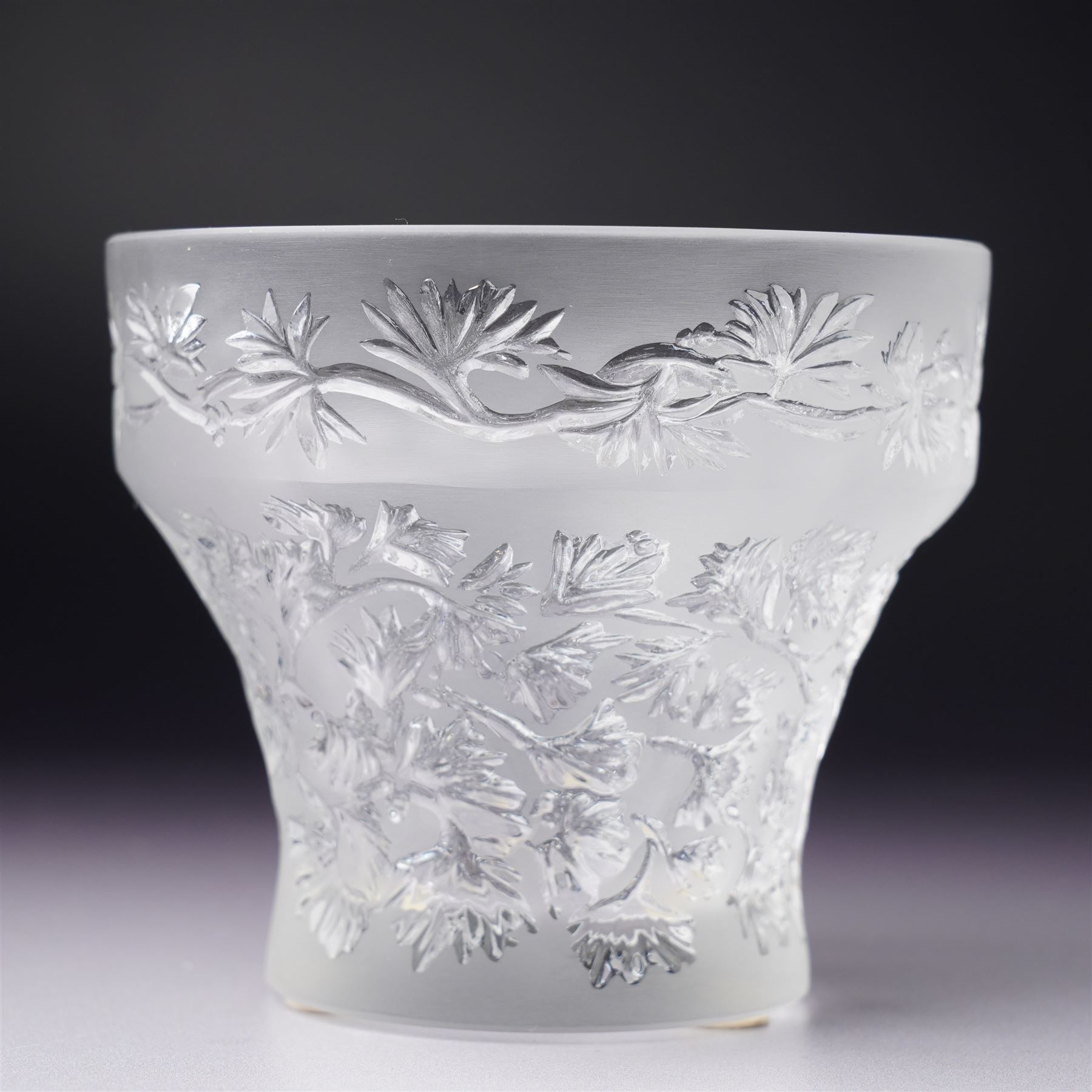 Three Lalique frosted glass tea light holders, decorated with the coriander and basil patterns, and another with trailing leaves, marked Lalique France to base, H7.5cm