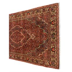 Persian Bidjar crimson ground rug, thick woollen pile, the field decorated with repeating Herati motifs within cusped outlines, the guarded border decorated with repeating flower head motifs