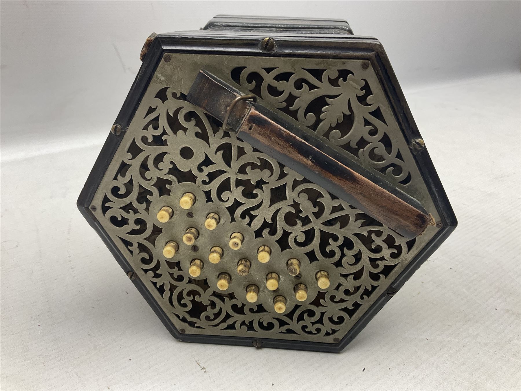 19th century Lachenal concertina of hexagonal form with fretworked nickel ends and thirty-four plus one bone buttons; straps marked Lachenal & Co Makers London and wooden handle stamped English Make Trade Mark L16cm