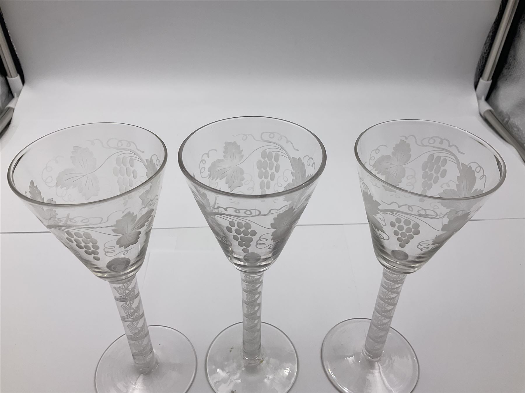 Set of three 18th century style wine glasses, each with funnel bowl etched with fruit vine, upon a double series air twist stem and circular foot, H17cm
