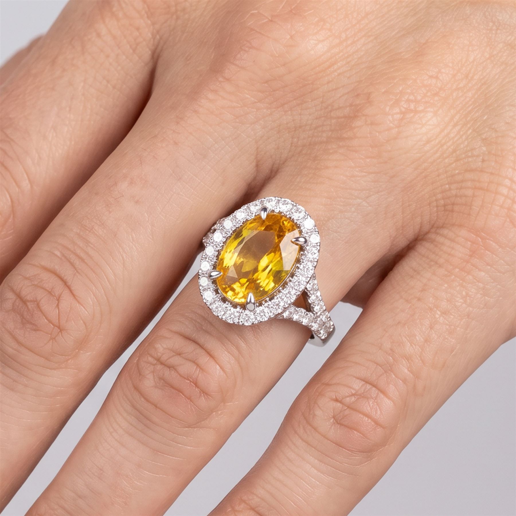 18ct white gold yellow sapphire and diamond ring, single oval cut sapphire of approx 4.20 carat, surrounded by round brilliant cut diamonds and split diamond set shoulders, hallmarked, with World Gemological Institute report