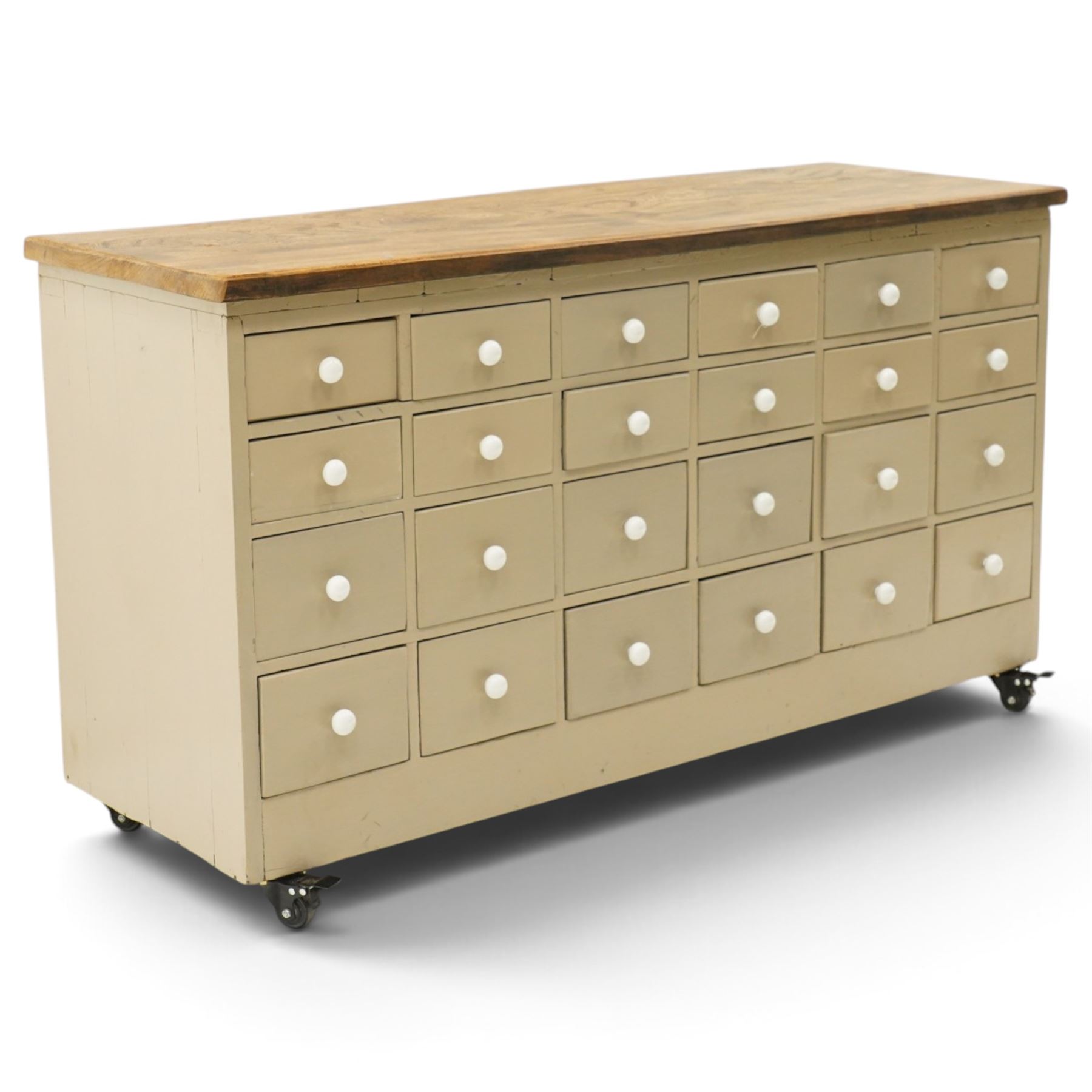 20th century haberdashery style chest, solid elm top over twenty-four assorted drawers with white ceramic knob handles, painted sage green carcass, raised on castors