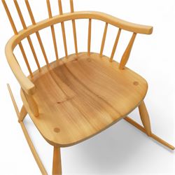 Mid 20th century Windsor ash rocking armchair, in the manner of Ercol, with curved cresting rail above nine stick spindles, shaped and chamfered paddle arms, figured shaped seat, raised on turned legs joined by twin side stretchers and mounted on curved rockers