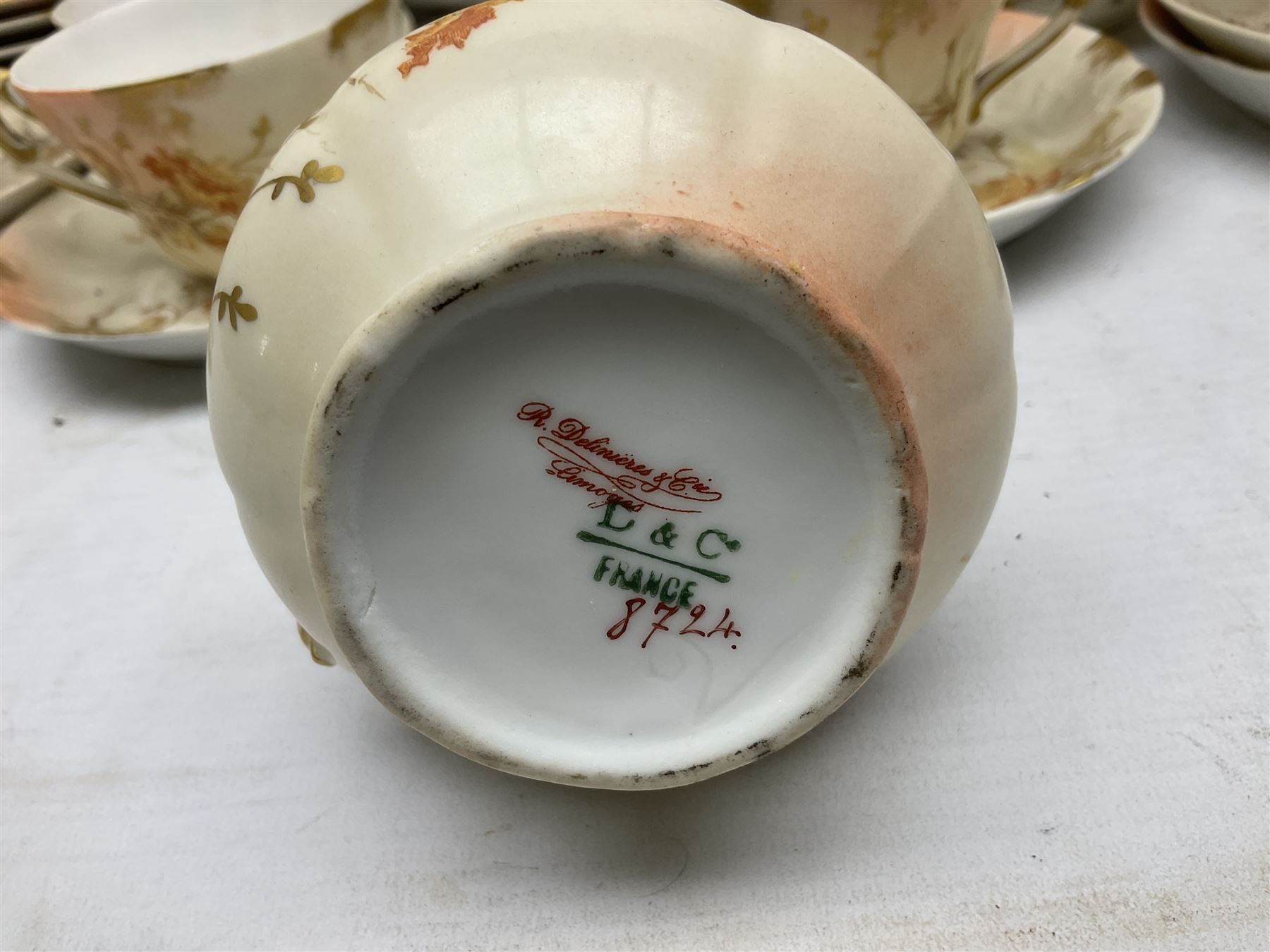 Early 20th century Limoges part tea service, decorated with floral sprays and gilt on merging peach and white ground, comprising six teacups, twelve side plates, six smaller plates, milk jug, open sucrier, slop bowl and two cake plates, many marked R Delinieres Limoges D&C France to base