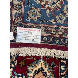 Central Persian Yazd hand-knotted rug, madder red field with scrolling vines, palmettes, and rosettes around a cusped lozenge medallion within a blue ground border of palmettes and flowerheads, 366cm x 250cm