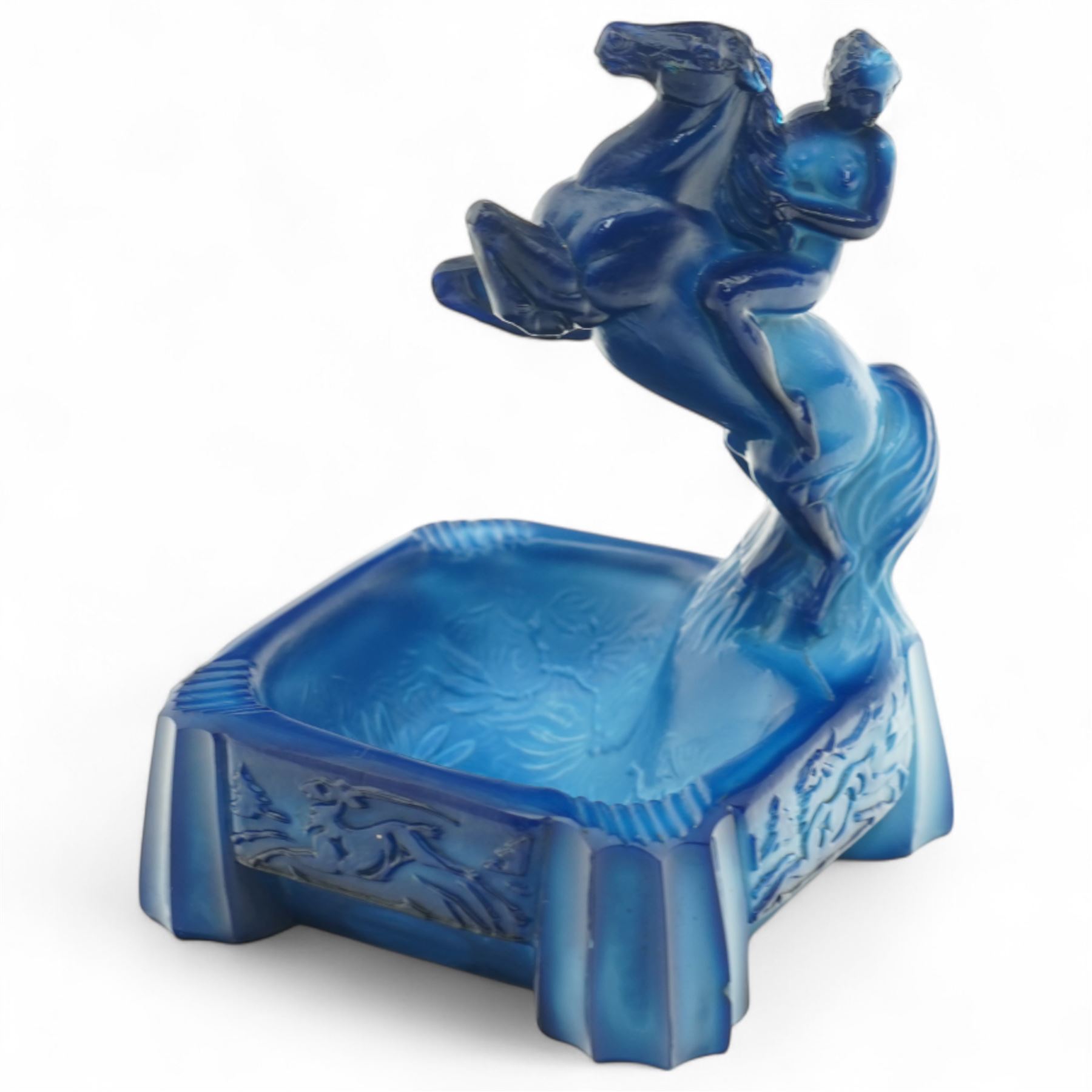 Early 20th century art deco style lapis glass ashtray, in the manner of Frantisek Pazourek, depicting a nude maiden astride a reared horse, possibly Lady Godiva, the bowl with raised foliate decoration, each side panel depicting leaping deer in light relief, flat base with fluted corner decoration, W7cm