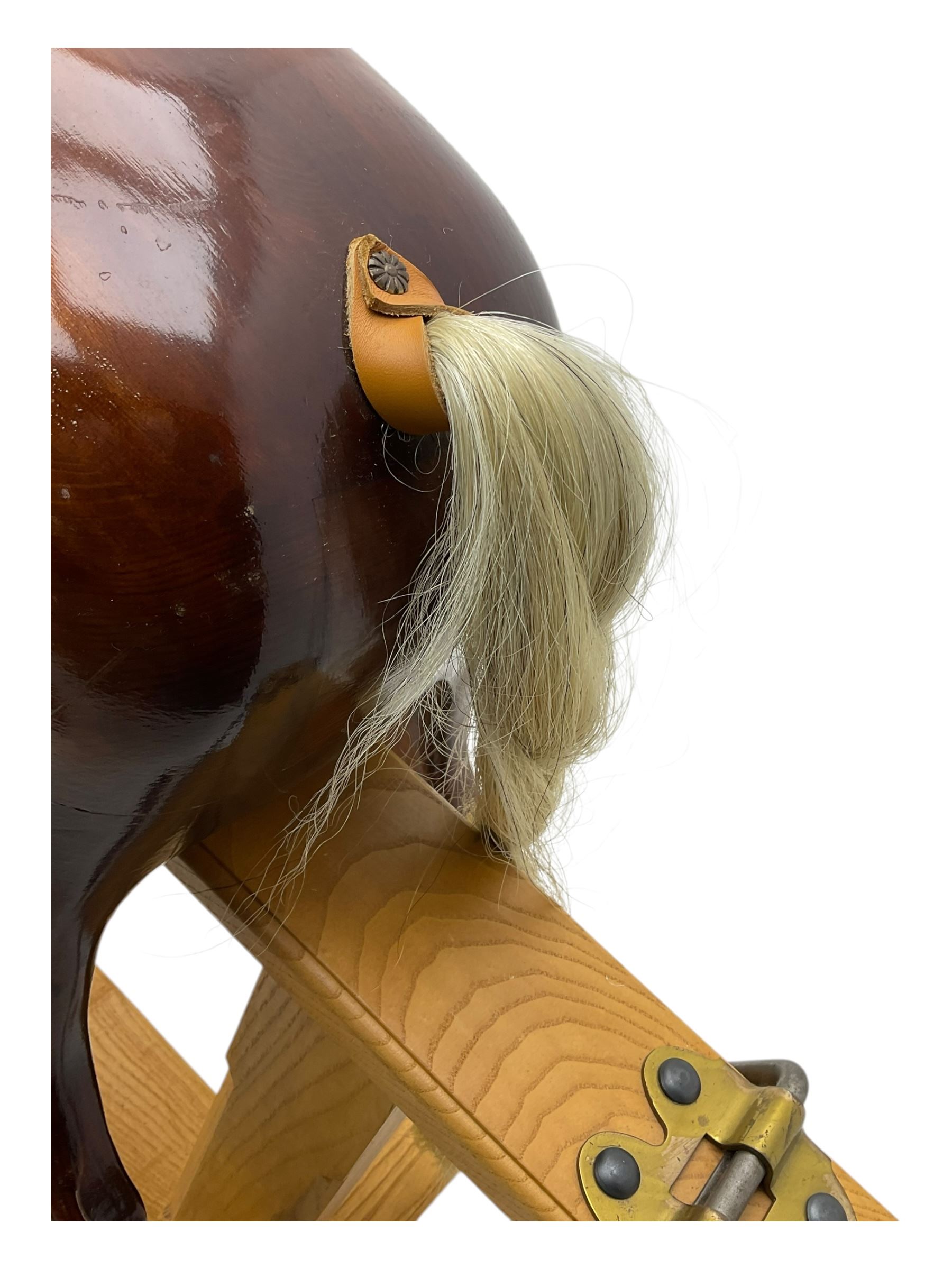 Contemporary carved wooden rocking horse, with leather saddle and bridle, horsehair mane and tail, raised on a pine stand with swing iron supports