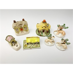 A group of Victorian and later figures, comprising Victorian Staffordshire money box in the form of a house, a Victorian Staffordshire pastille burner in the form of a house, three figures modelled as recumbent deer before trees, Staffordshire style model of a dog emerging from a kennel upon pen holder base, and Coalport pastille burned in the form of a house. (7). 