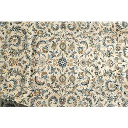 Central Persian Kashan hand-knotted carpet, ivory field profusely decorated with an all-over scrolling vine, palmette, and lotus design in shades of soft blue, pale gold, and green within floral borders
