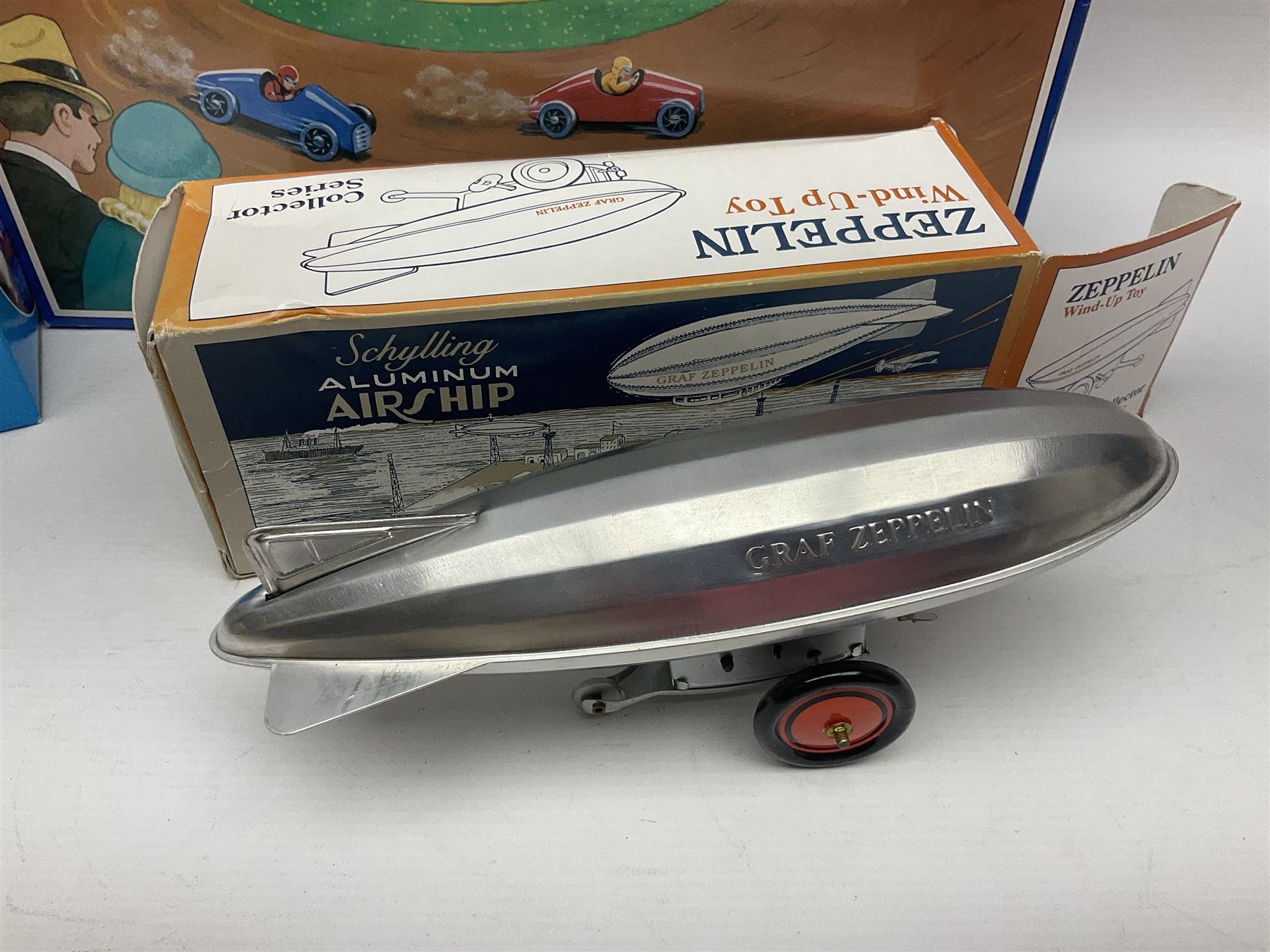 Schylling - six tinplate models comprising Sir Ian’s Bluebird racing car, Speedway Auto Racer, two Aluminium Airships, Tin Speedboat and Ernest in the Music Box; all in original boxes 