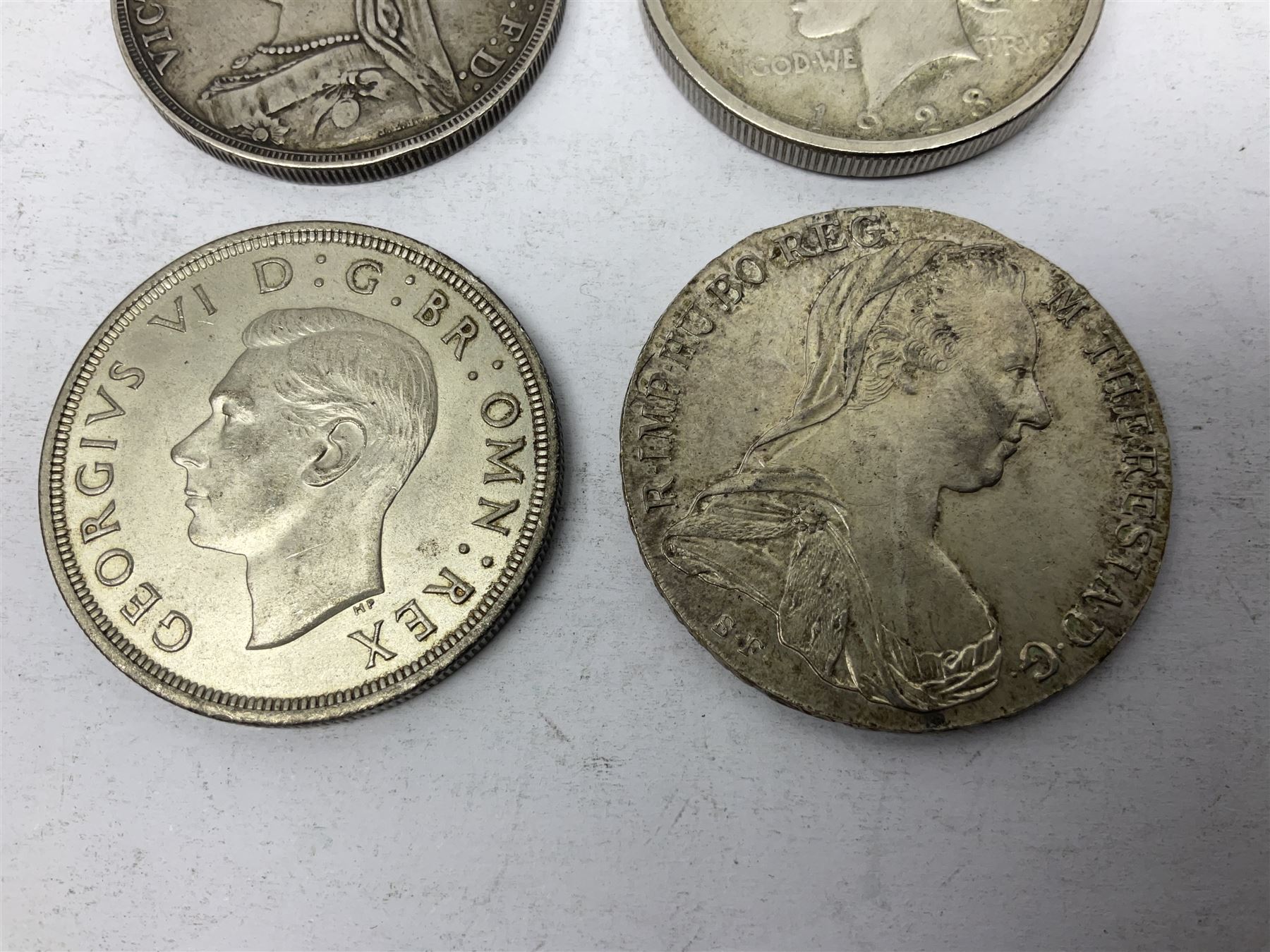 Four silver World coins comprising Queen Victoria 1889 crown, King George VI 1937 crown, Marie Thaler 1780 restrike, and mounted United States of America 1928 peace dollar 