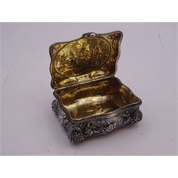Late 19th century German Hanau silver box, of shaped rectangular form, embossed throughout, the hinged cover decorated with a central oval panel depicting a genre scene with musicians, the corners detailed with masks, the sides detailed with conforming figures and musical trophies, opening to reveal a gilt interior, with Hanau marks for Neresheimer & Sohne, and hallmarked B Muller & Son, London import 1907, approximate weight 3.32 ozt (103.4 grams)