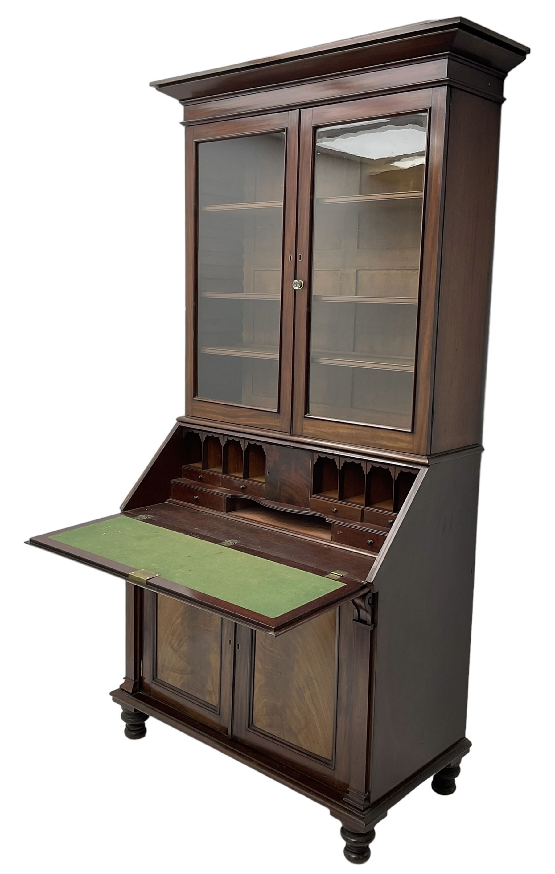 Early 19th century figured mahogany bureau bookcase, projecting splay moulded cornice over three adjustable shelves enclosed by two glazed doors, fall front revealing pigeonholes, cupboard and drawers, pull-out strays with scroll carved terminals, double cupboard with two panelled doors, on turned feet 