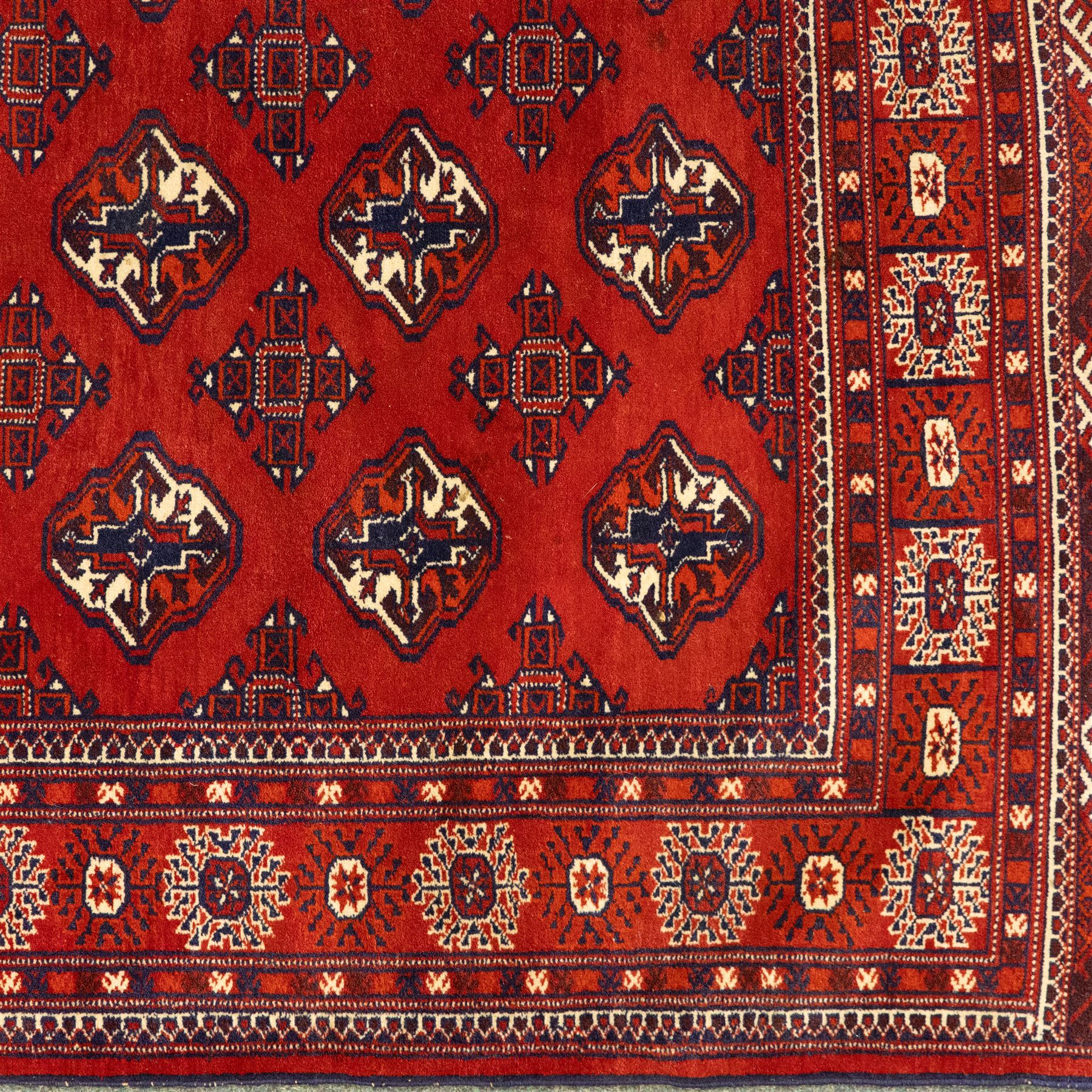 Three rugs,  comprising a Baluch rug in crimson ground, 179x97cm, a Tekke Bokhara rug in crimson ground, 201x132cm, and a Bokhara rug in ochre ground, 125x175cm 