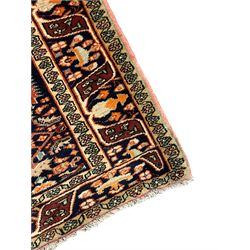 North West Persian Bidjar rug, orange peach ground extended field on indigo ground, decorated with floral Herati motifs, repeating waved border decorated with stylised plant motifs