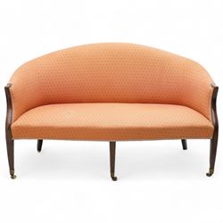 George III Hepplewhite design settee, arched back over serpentine set, upholstered in salmon fabric with repeating pattern, on square tapering supports with brass cups and castors 