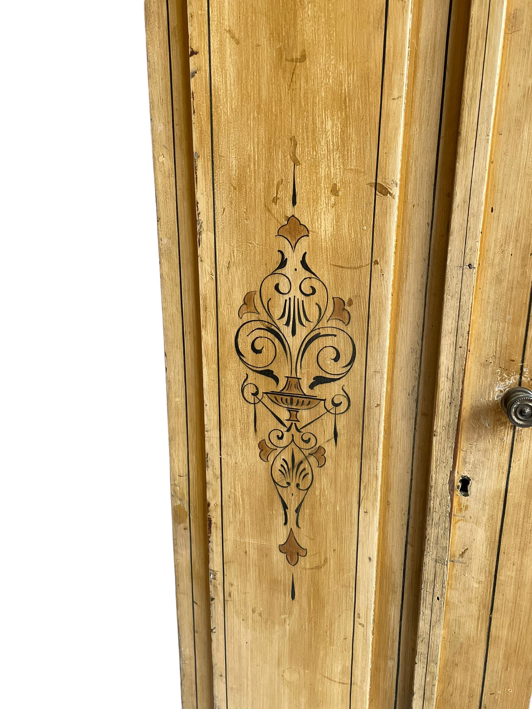 19th century painted pine wardrobe, the projecting cornice over mirror glazed door, with painted decoration depicting scrolling foliate and urns, drawer to base on skirt