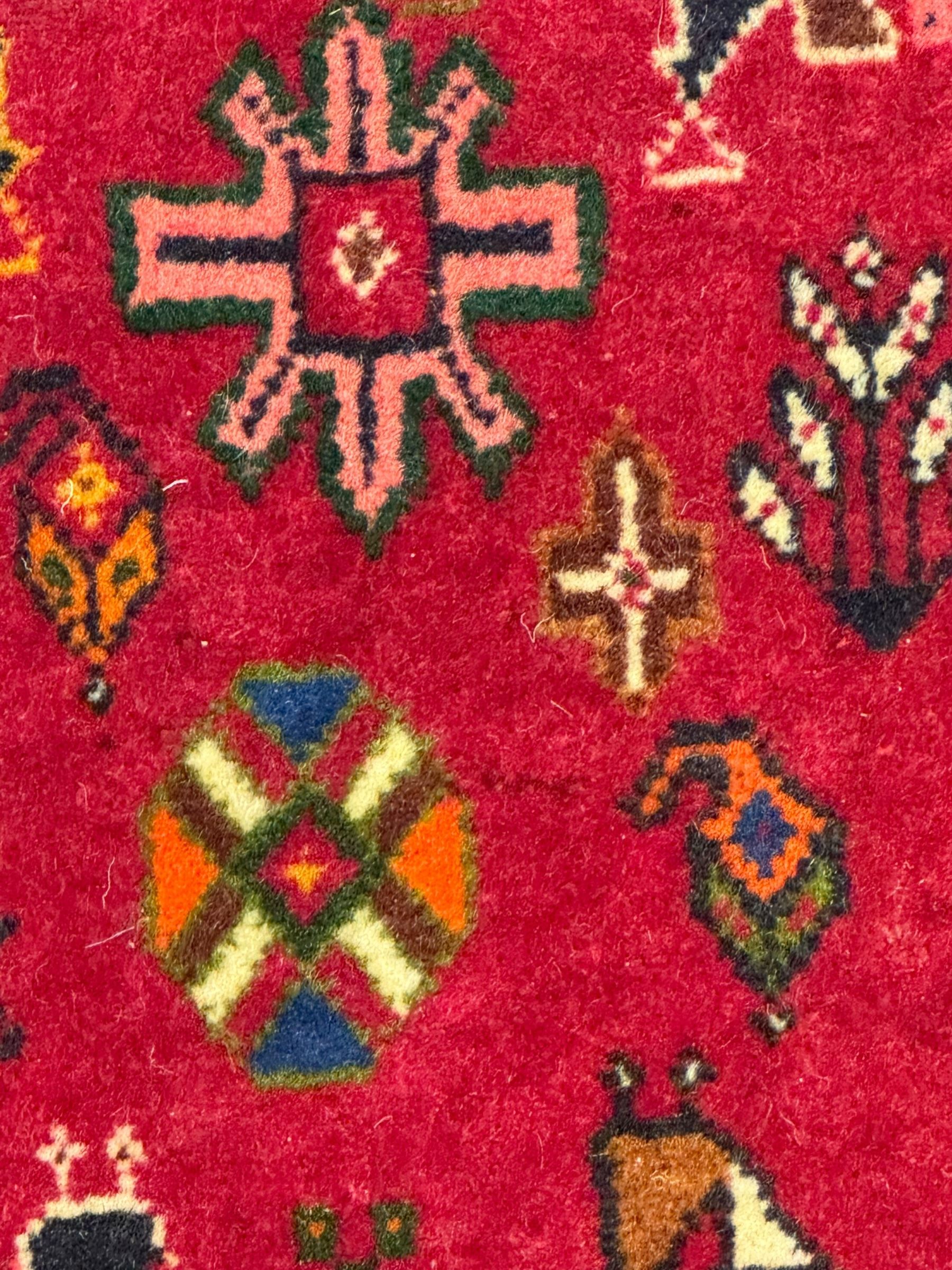 South West Persian Qashqai red ground runner, the crimson field decorated with three connected lozenges, surrounded by small stylised motifs of bird and plants, indigo spandrels with further stylised motifs, the border with repeating floral design 
