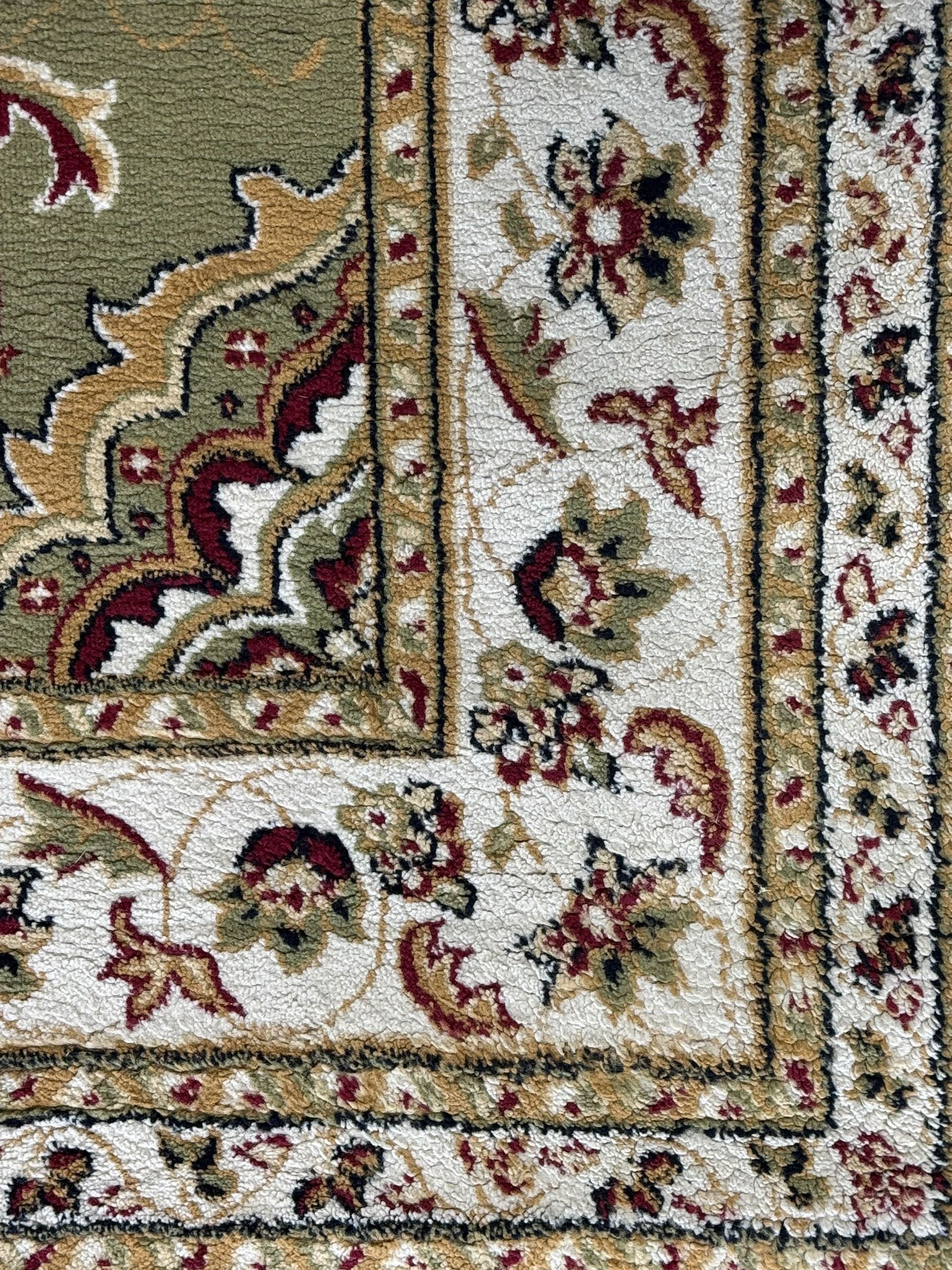 Turkish Sincerity Royale green ground rug, the field decorated with a central floral medallion surrounded by scrolling floral motifs in shades of cream, beige, and burgundy, spandrels filled with matching floral designs, the border featuring a series of floral patterns on a cream ground, finished with green edges