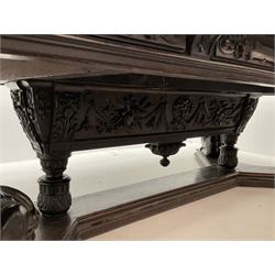 Large 19th century carved oak library table, the rectangular top with lunette carved edge over cartouche panelled and carved  scroll frieze, the central tapering rectangular support relief carved with masks and garlands, on four carved seated lion supports at each corner, on flat angular stretcher with recessed castors stamped ‘Bartholomew & Fletcher, London’