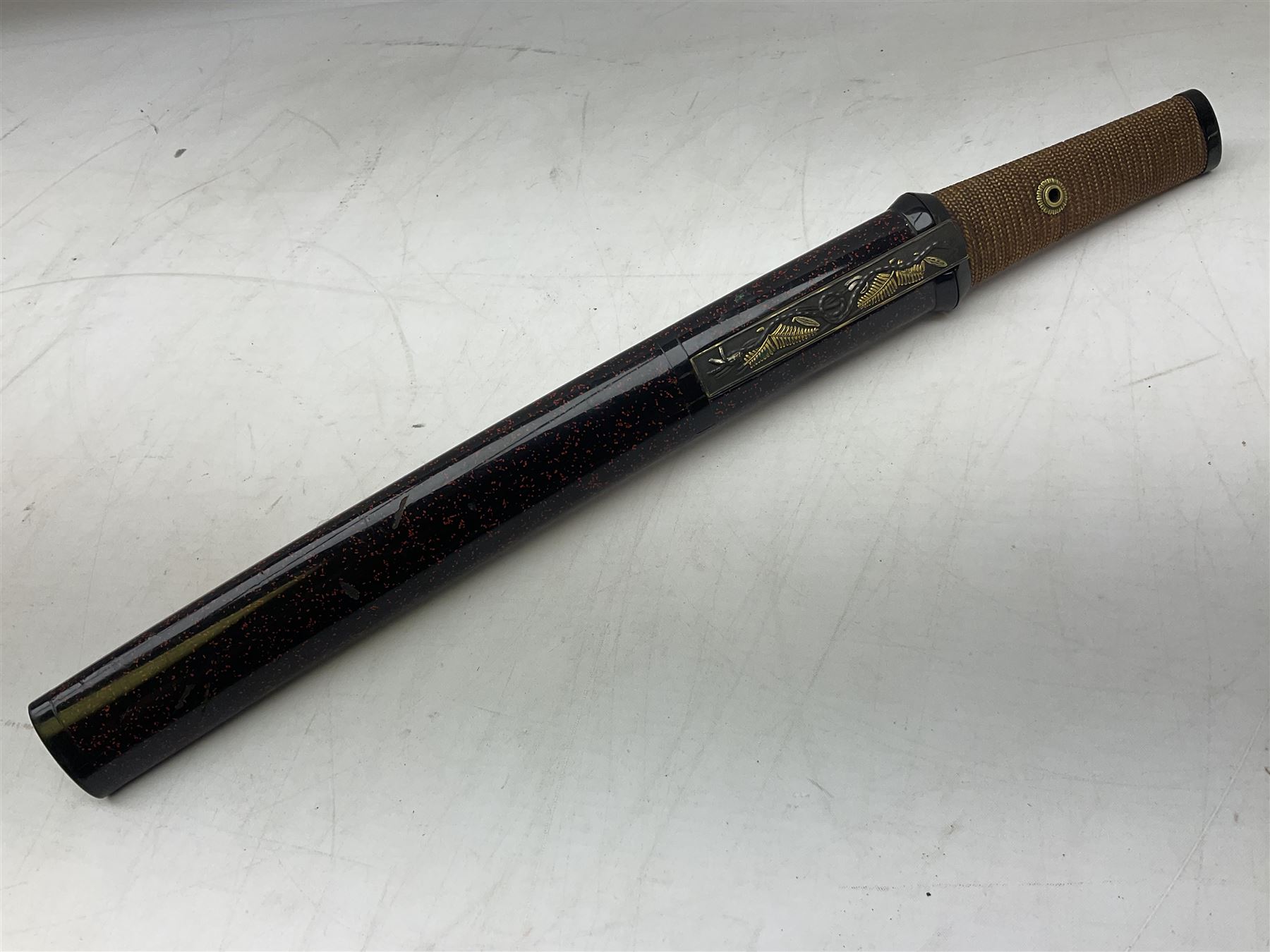 Japanese Tanto with 28.5cm steel blade and cord bound grip; in red spotted black lacquer saya containing a kogai knife with etched characters to the blade and ornate fern leaf and snake handle