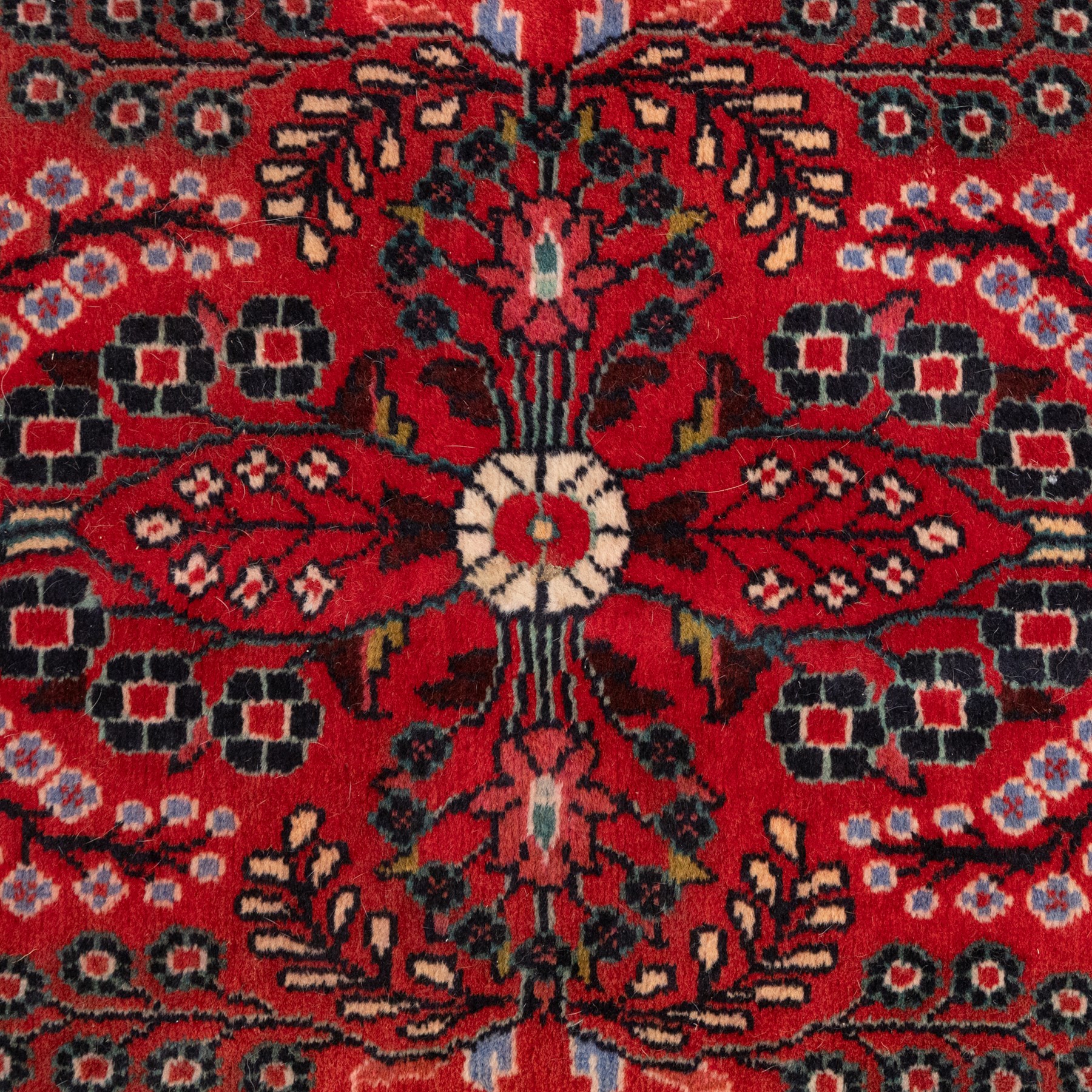 Two Persian rugs, the larger with a crimson field decorated with three linked indigo medallions amongst flowering tendrils, shaped floral spandrels and an indigo palmette border, (161cm x 129cm), the smaller with a crimson field centred by an ivory rosette amongst stylised flowering plants, within a dark floral border, (114cm x 79cm) (2)
