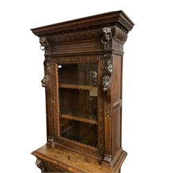 Victorian heavily carved oak cabinet, projecting cornice over gadroon frieze, lion mask and figure carved uprights, the single glazed cupboard fitted with three shelves, above single drawer and lower cupboard enclosed by panelled door with geometric mouldings and masks 