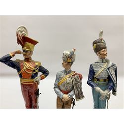 Group of seven Capodimonte figures of soldiers, to include four Bruno-Merli examples including Officer of the 12th Lancers 1820 and Captain of the 18th Hussars 1815, both raised upon ornate gilt plinths bearing British monarch motto in Latin 'Dieu et mon droit', and three further similar, all with crowned N mark beneath, tallest H32cm