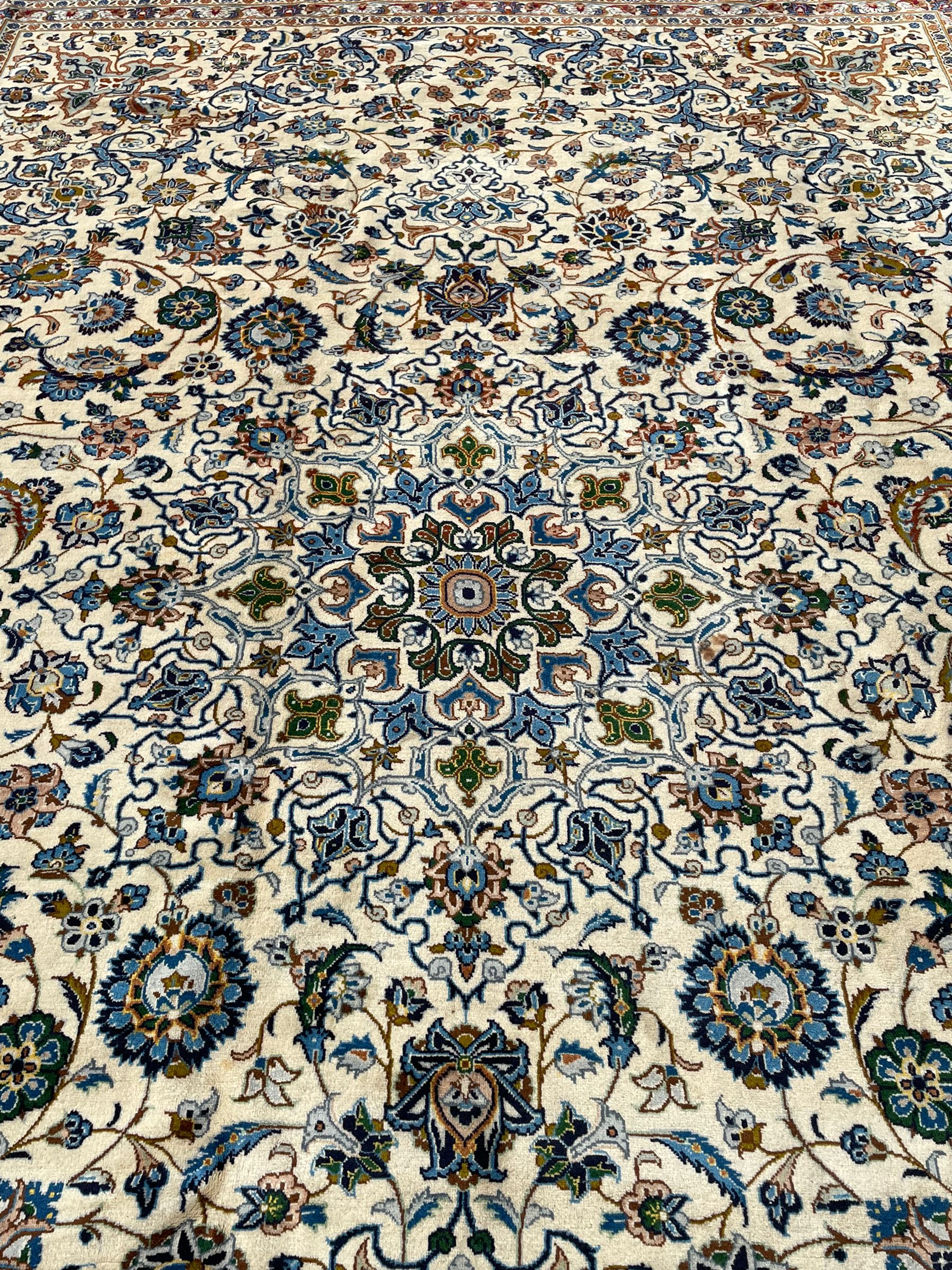 Persian Kashan ivory ground carpet, the interlaced foliate medallion surrounded by trailing plant motifs interlaced with scrolls, the guarded border with repeating stylised flower heads