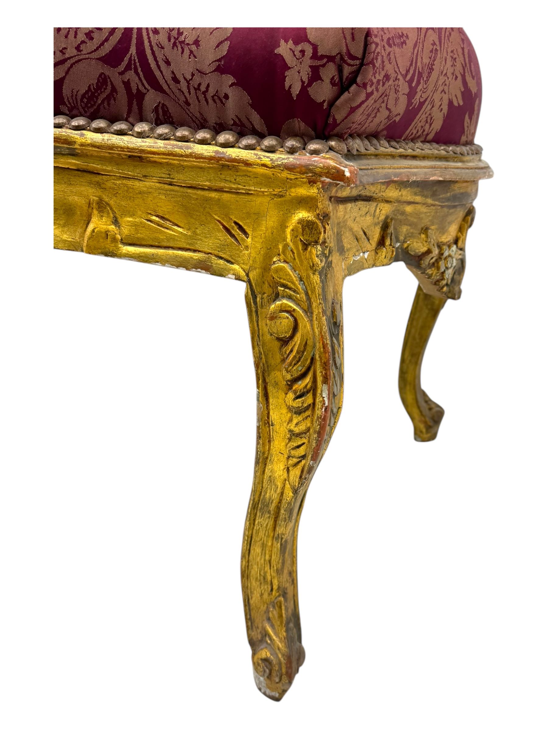 Pair of Louis XV-design giltwood stools, each upholstered in red damask fabric with slight variations in patterns, the carved frames adorned with scrolling foliage and shell motifs, raised on cabriole supports
