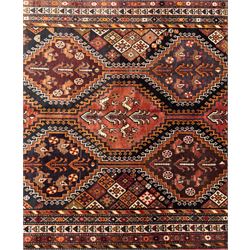 Southwestern Persian Qashqai hand-knotted carpet, the field with a lattice of hexagonal medallions in rust, indigo, and ochre, each containing stylised tree and floral motifs, flanked by lozenge panels with geometric designs, enclosed by multiple borders with rosettes and leaf motifs