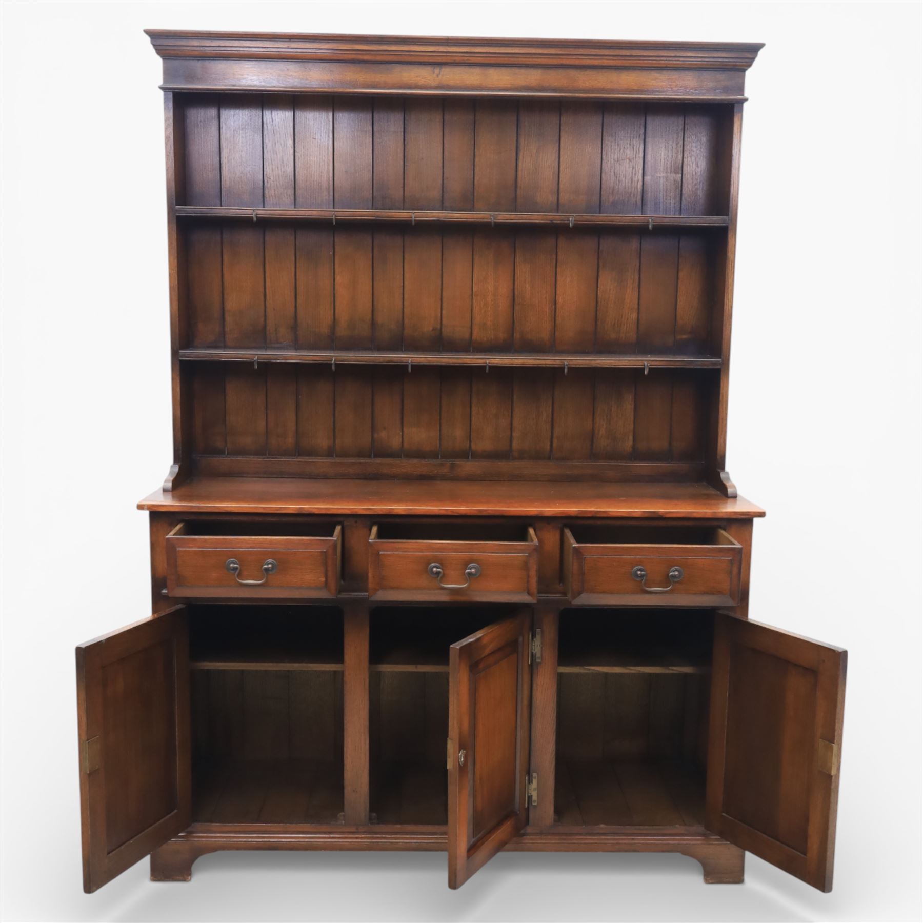 Georgian style oak dresser, the moulded cornice above two open plate racks, upon base with rectangular top above an arrangement of three frieze drawers fitted with brass swan neck handles, and three panelled cupboard doors, upon bracket feet