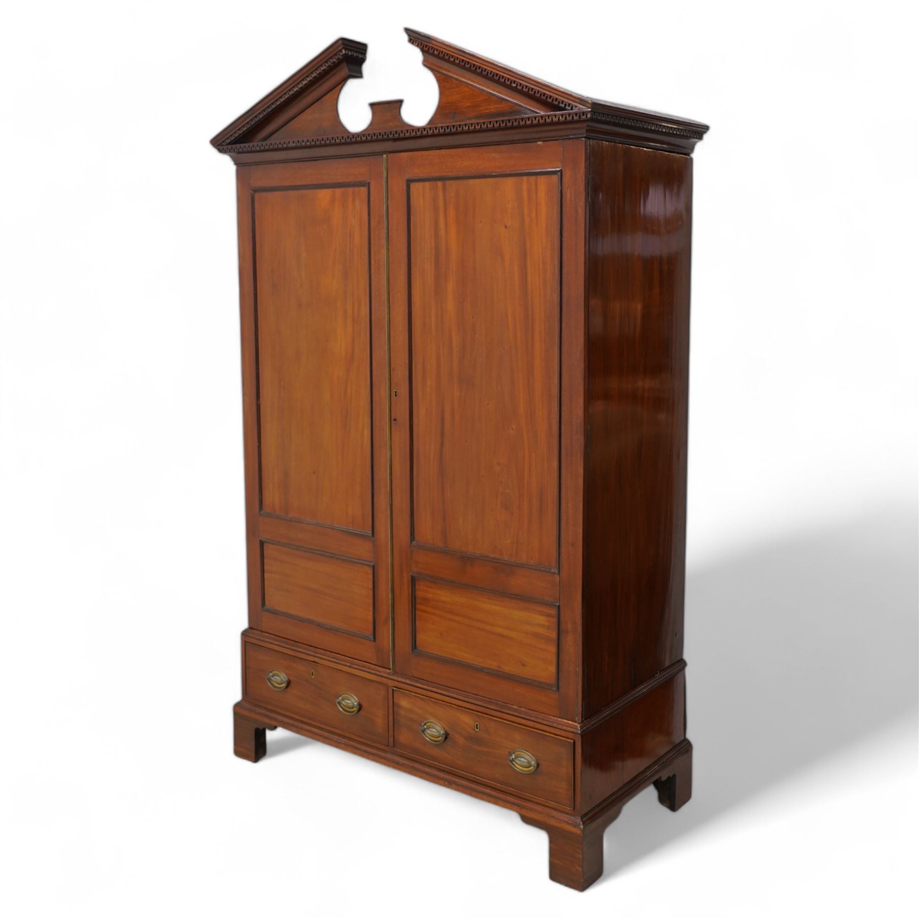 George III mahogany wardrobe, broken sloped arch pediment with dentil moulding over two panelled doors, the base fitted with two cock-beaded drawers, on bracket feet, knock-down construction 