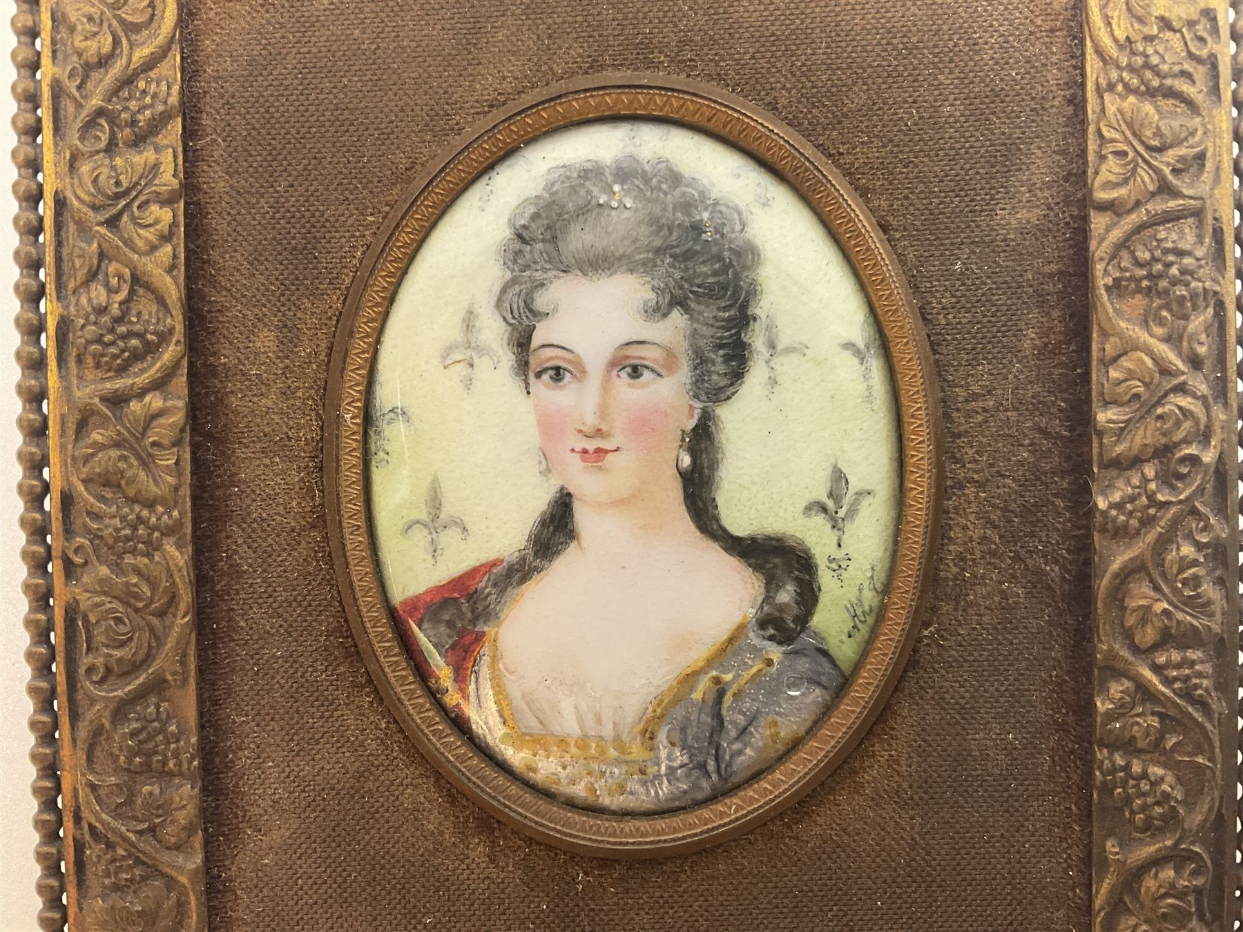 19th century portrait miniature on enamel, depicting a Georgian lady in period dress, hand painted with gilt detailing, in gilt frame with fruiting vine details, overall H13.7cm