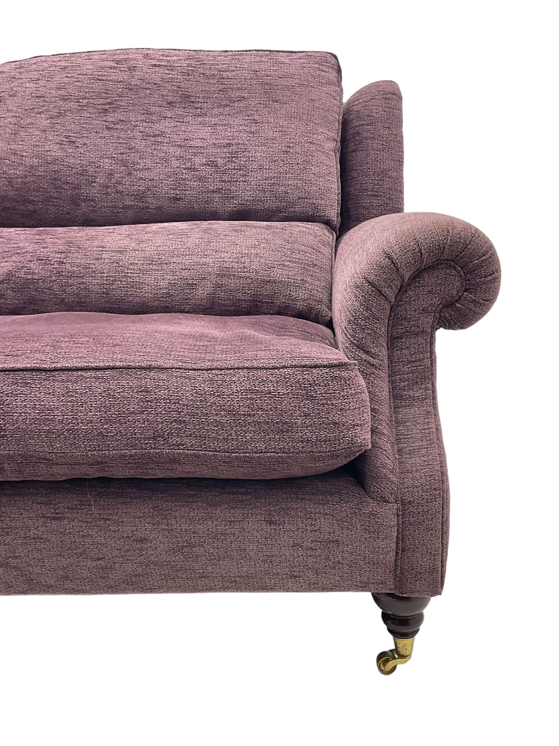Parker Knoll - pair of large two-seat sofas upholstered in purple fabric, turned mahogany finish front feet with brass cups and castors 