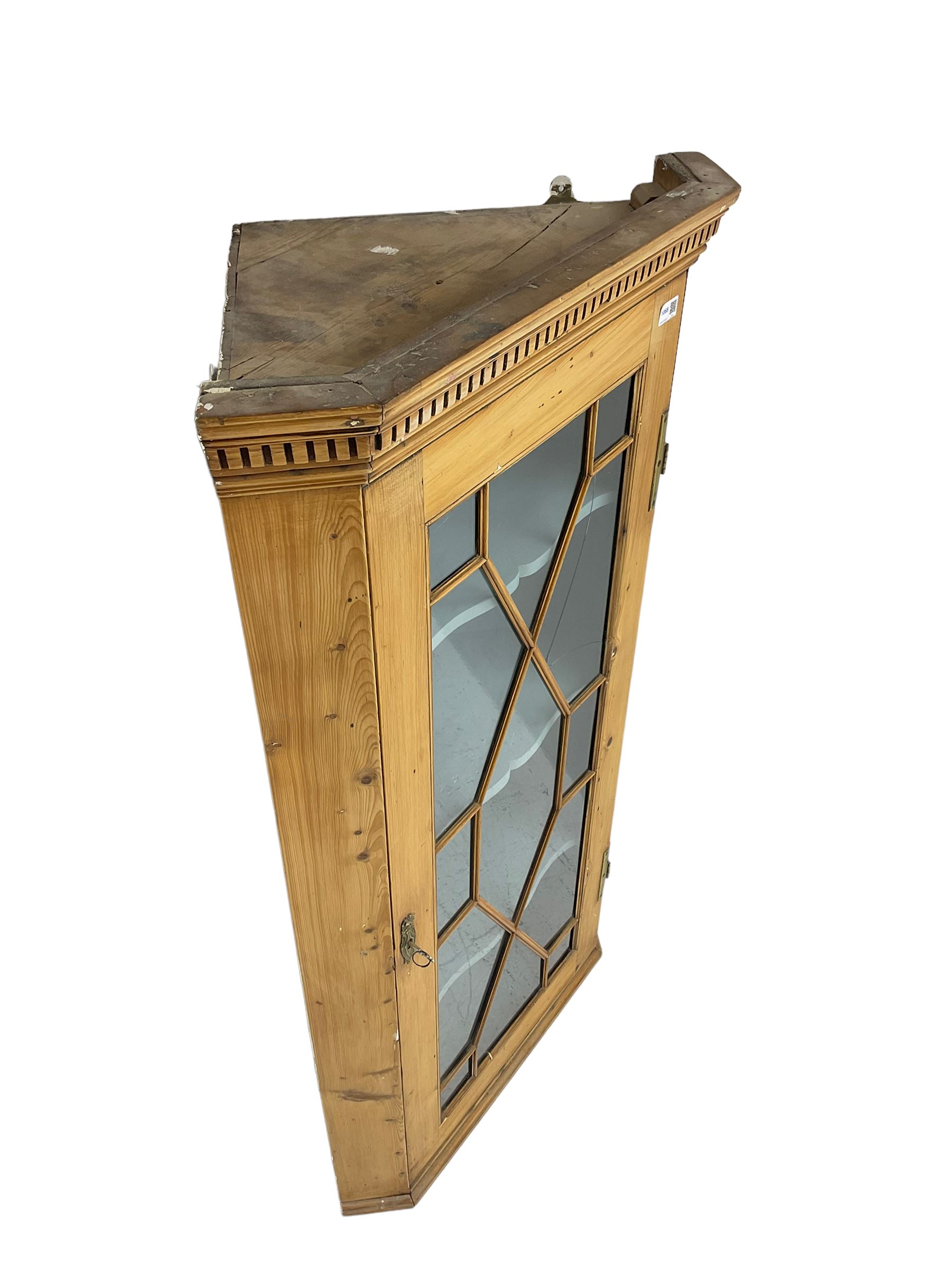 Early 19th century pine corner cabinet, projecting dentil cornice over astragal glazed door