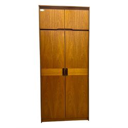 William Lawrence - mid-20th century teak double wardrobe, upper storage section over twin doors featuring recessed handles and contrasting horizontal panel, enclosing a hanging rail compartment, on plinth base with concealed castors