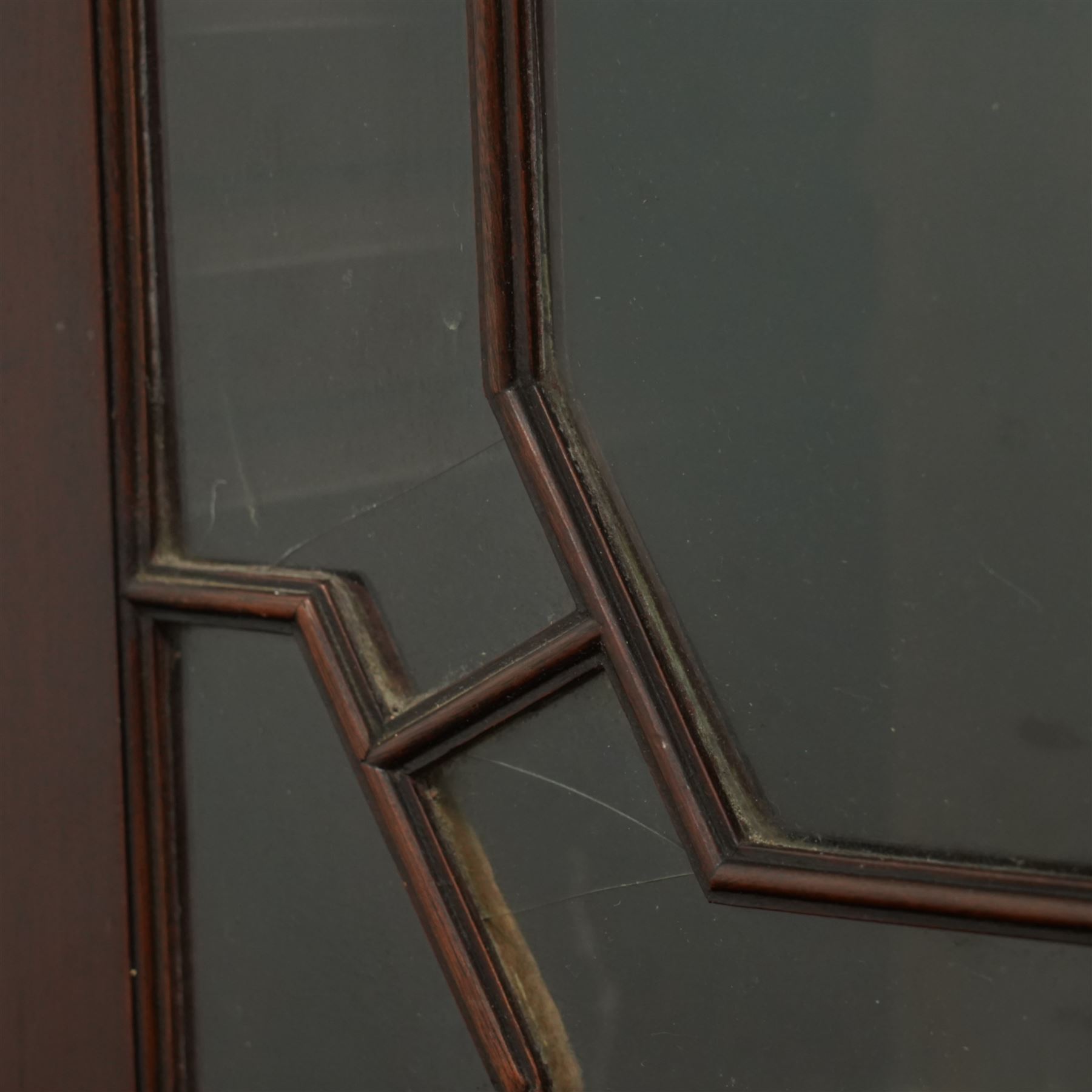 Early 20th century Chippendale design mahogany bookcase, projecting moulded cornice over four astragal glazed doors, the interior fitted with adjustable shelves, on bracket feet 