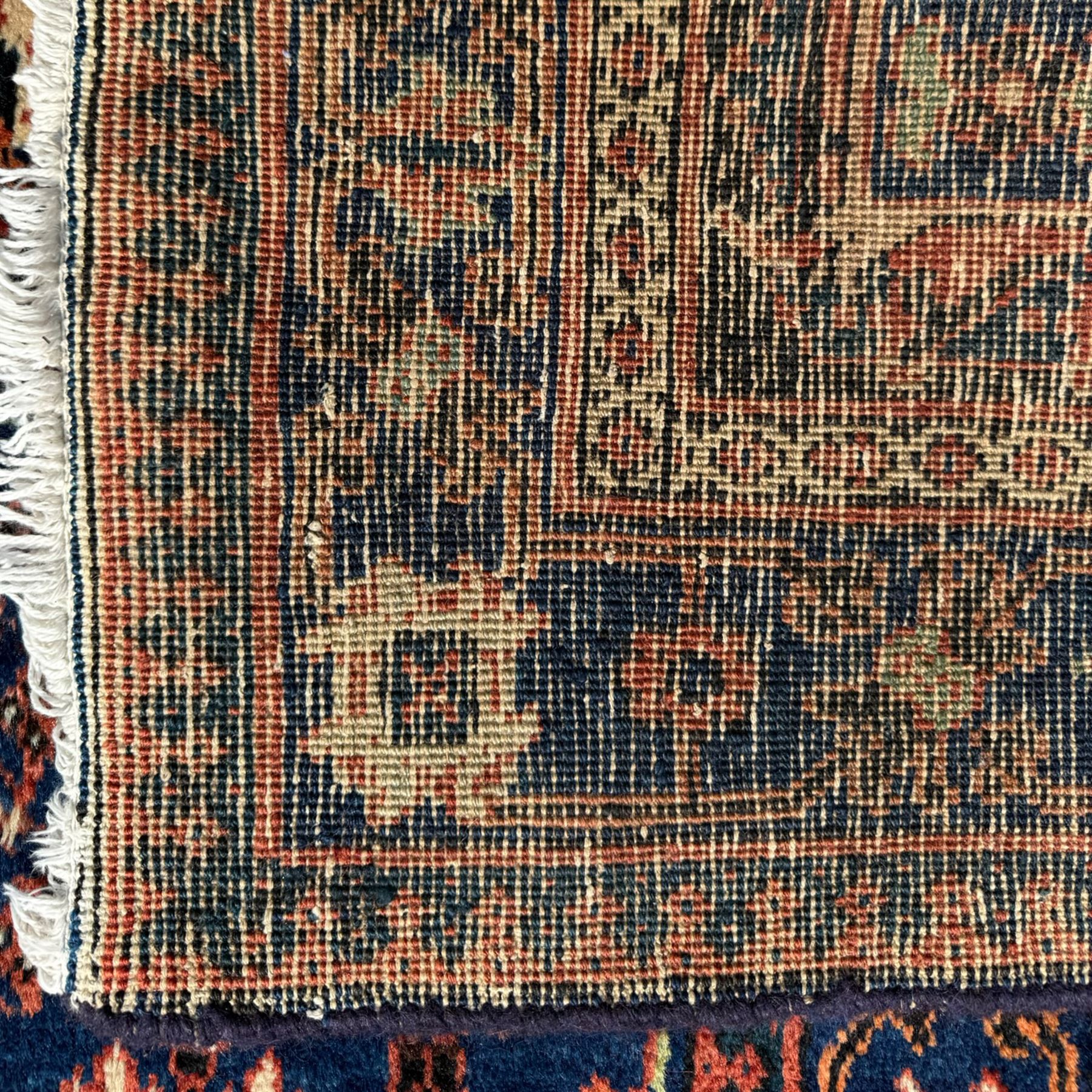 Joshgan Persian wool rug, with diamond-framed medallion, on a deep red field filled with geometric-shaped floral motifs and indigo-filled spandrels 
