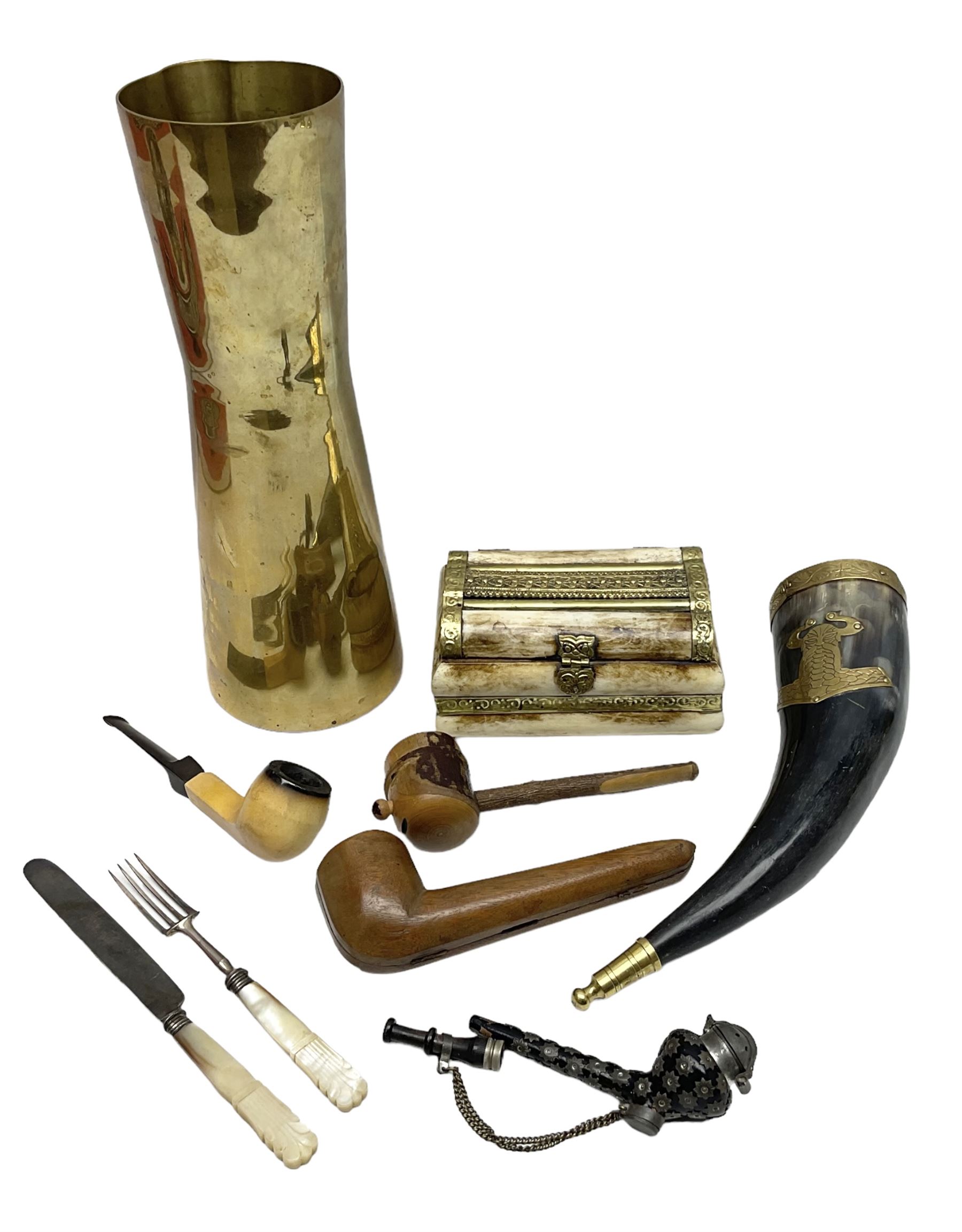 Swiss mountain hunters tobacco pipe with a horn mouthpiece, metal hinged pierced lid and brass chain, the black coated body adorned with small metal cow flowers, together with two other pipes and case, brass mounted horn, brass mounted bone box, carved mother of pearl handled knife and fork and brass jug