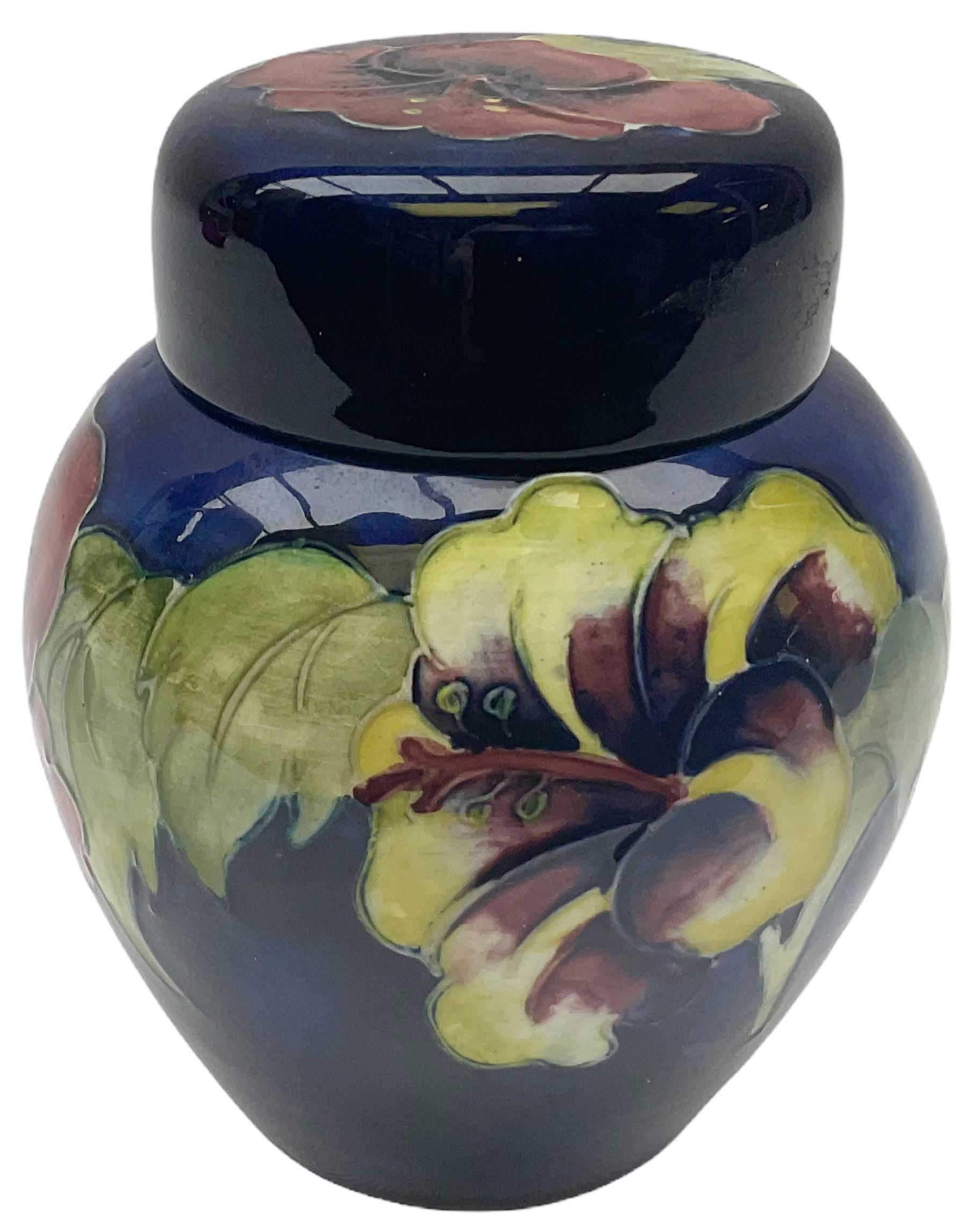 Moorcroft ginger jar, decorated in the Hibiscus pattern upon a blue ground, with paper label beneath detailed 'Potters to the late Queen Mary', H11cm.