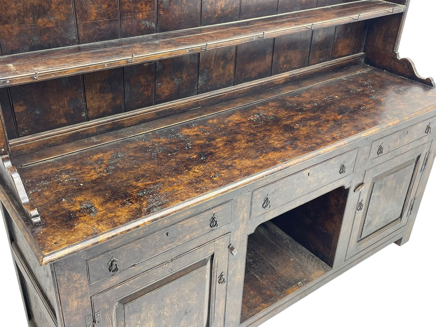 Bylaws of Leominster - 18th century design figured oak dog kennel dresser, the raised plate rack with projecting cornice over hooks and three tiers, moulded rectangular top over three drawers and two panelled cupboards, moulded frame and panelled sides, on stile supports