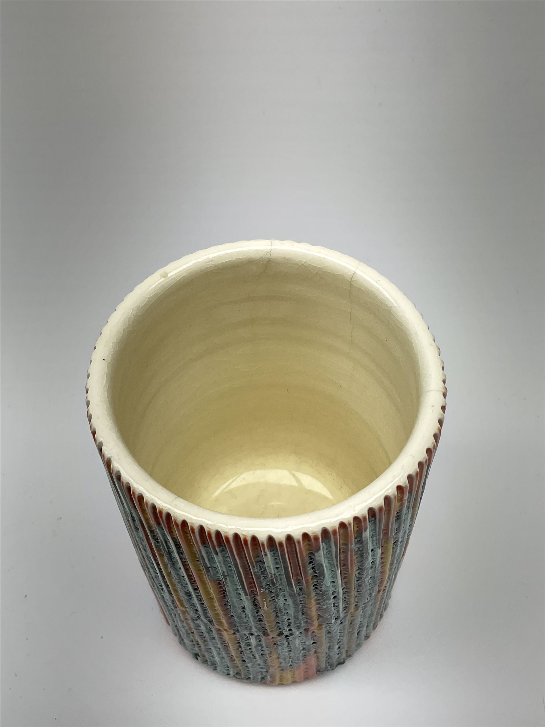 A Poole Pottery Delphis vase, shape 83, with textured effect in merging tones of red, yellow and blue, with printed mark beneath, H15cm.